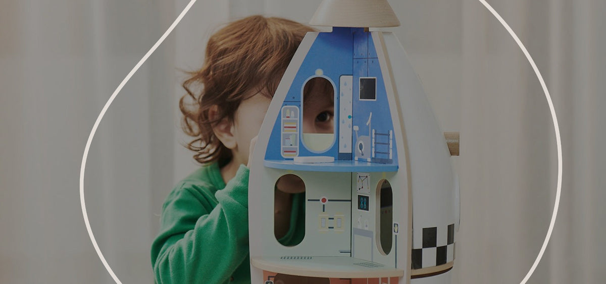 Child playing with a toy house shaped like a spaceship or rocket.