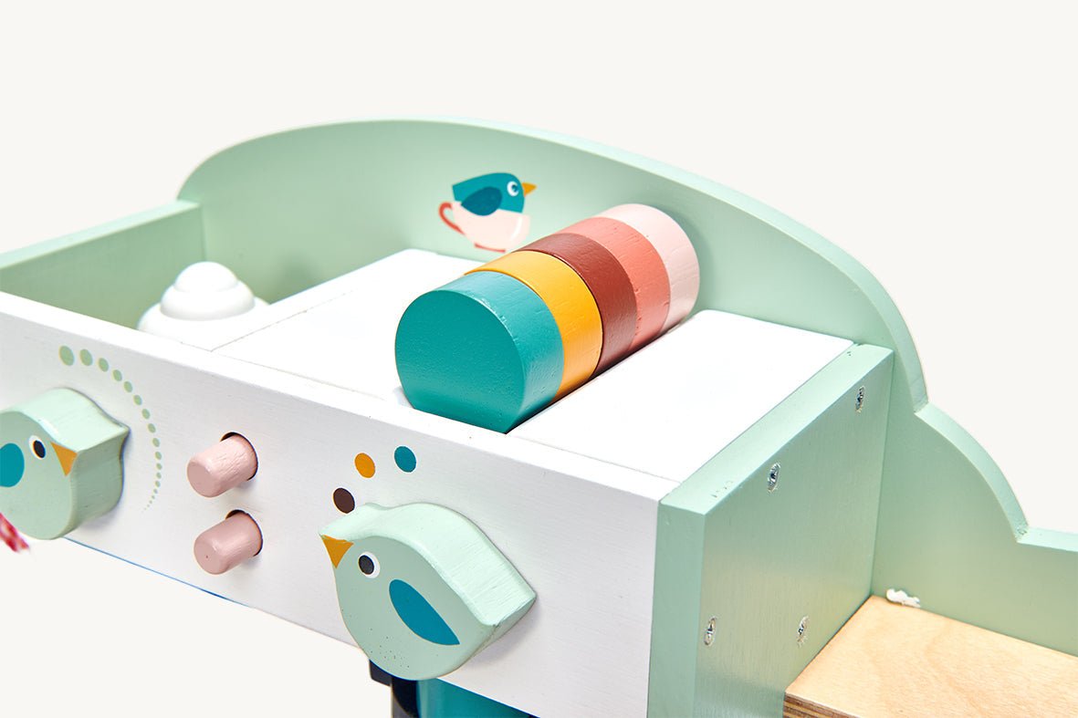 Children's play kitchen set with colorful toy pots and bird decorations on a light blue background