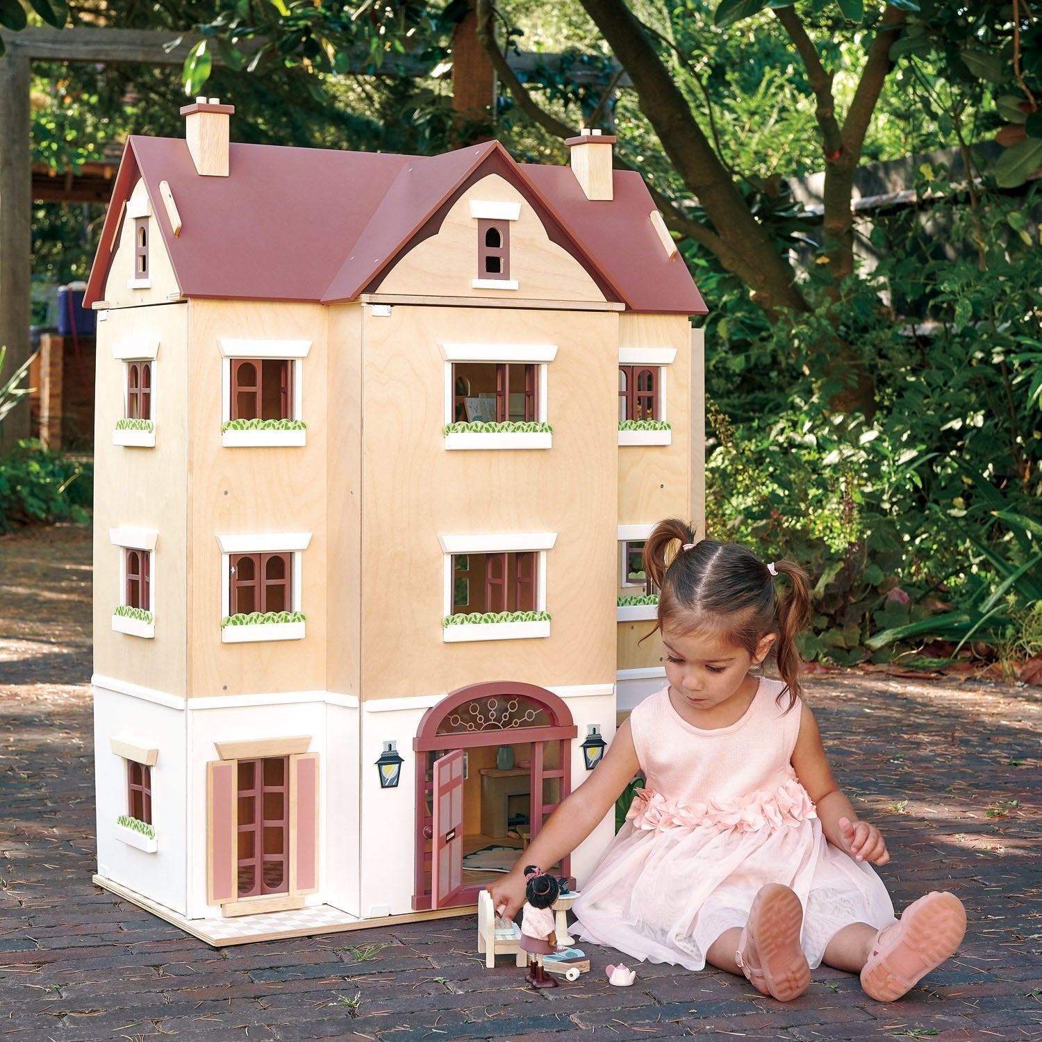 Child playing with a large dollhouse outdoors