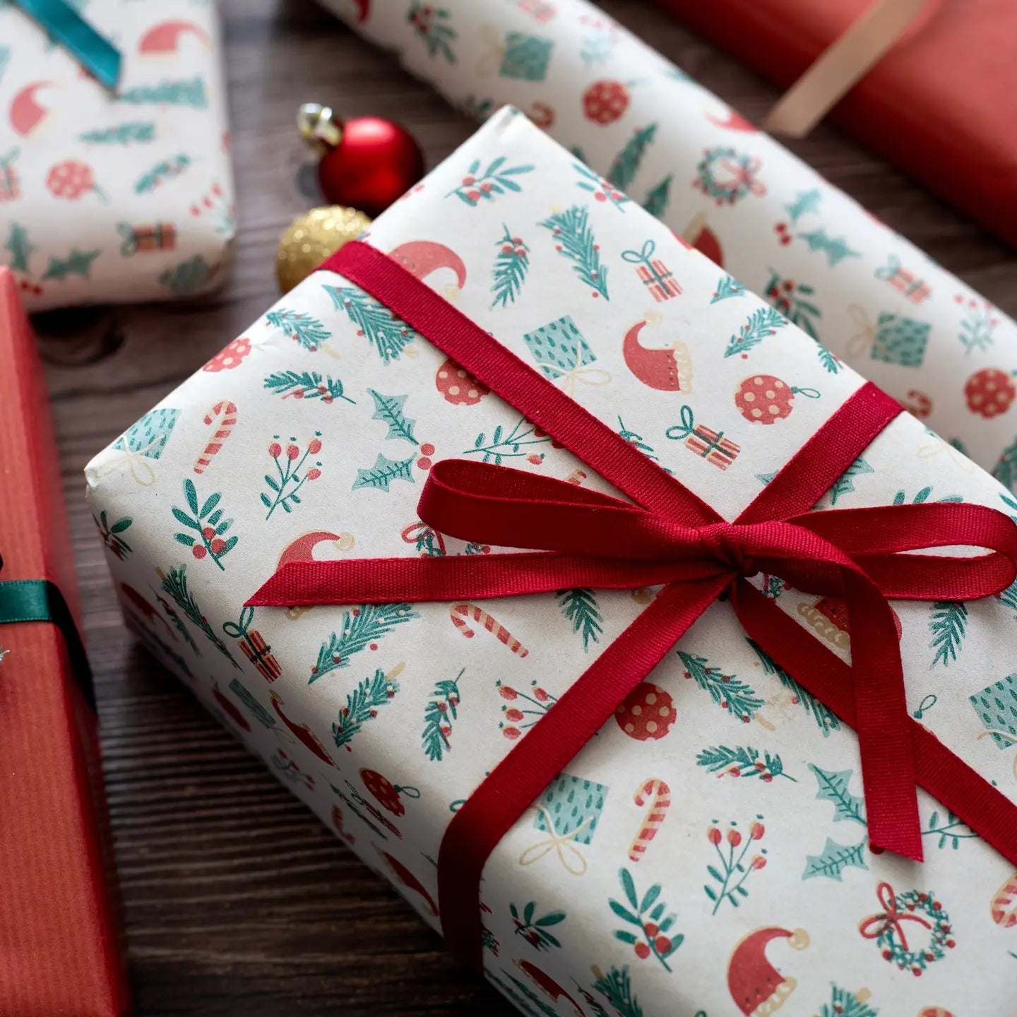 Gift box with festive pattern and red ribbon on a wooden surface
