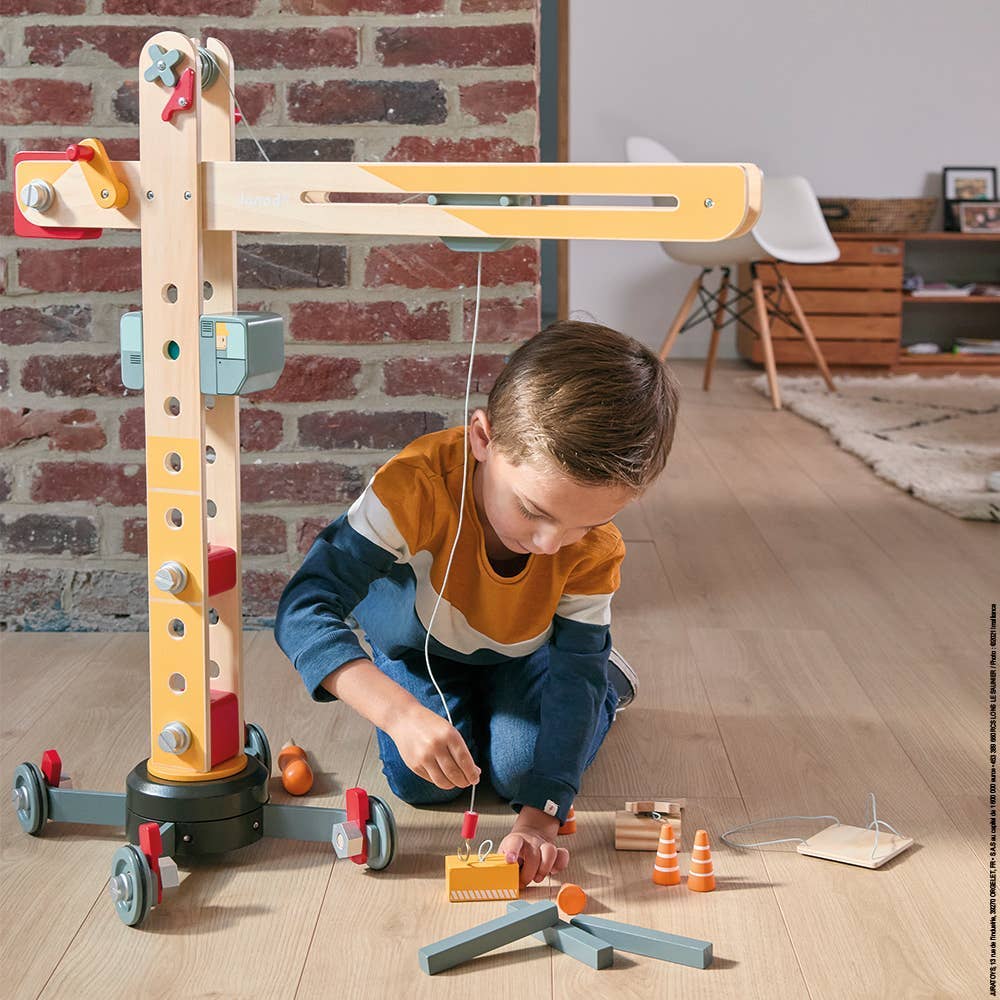 Child playing with a wooden toy setup on a wooden floor.