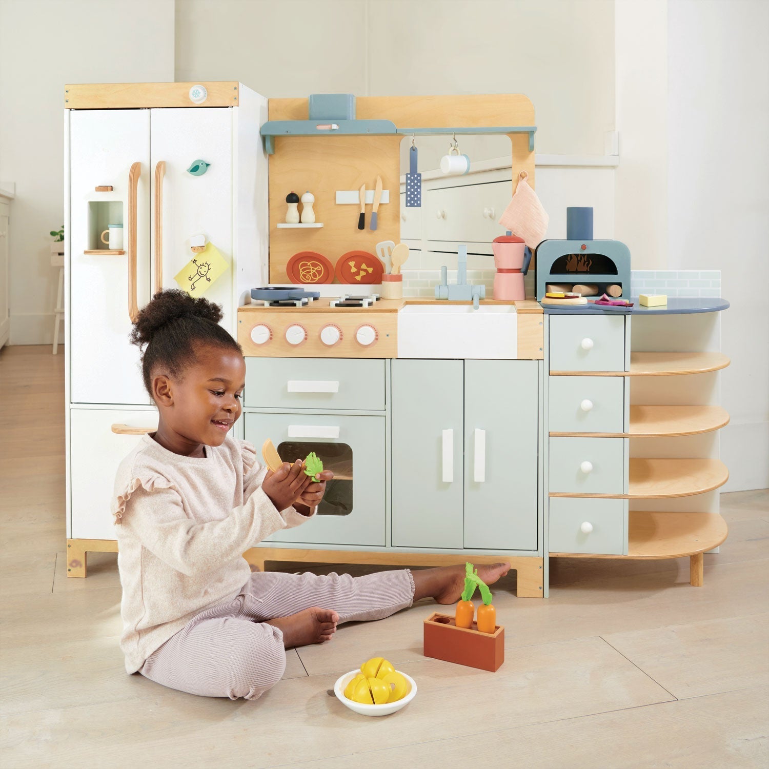Child playing with a toy kitchen set in a bright room