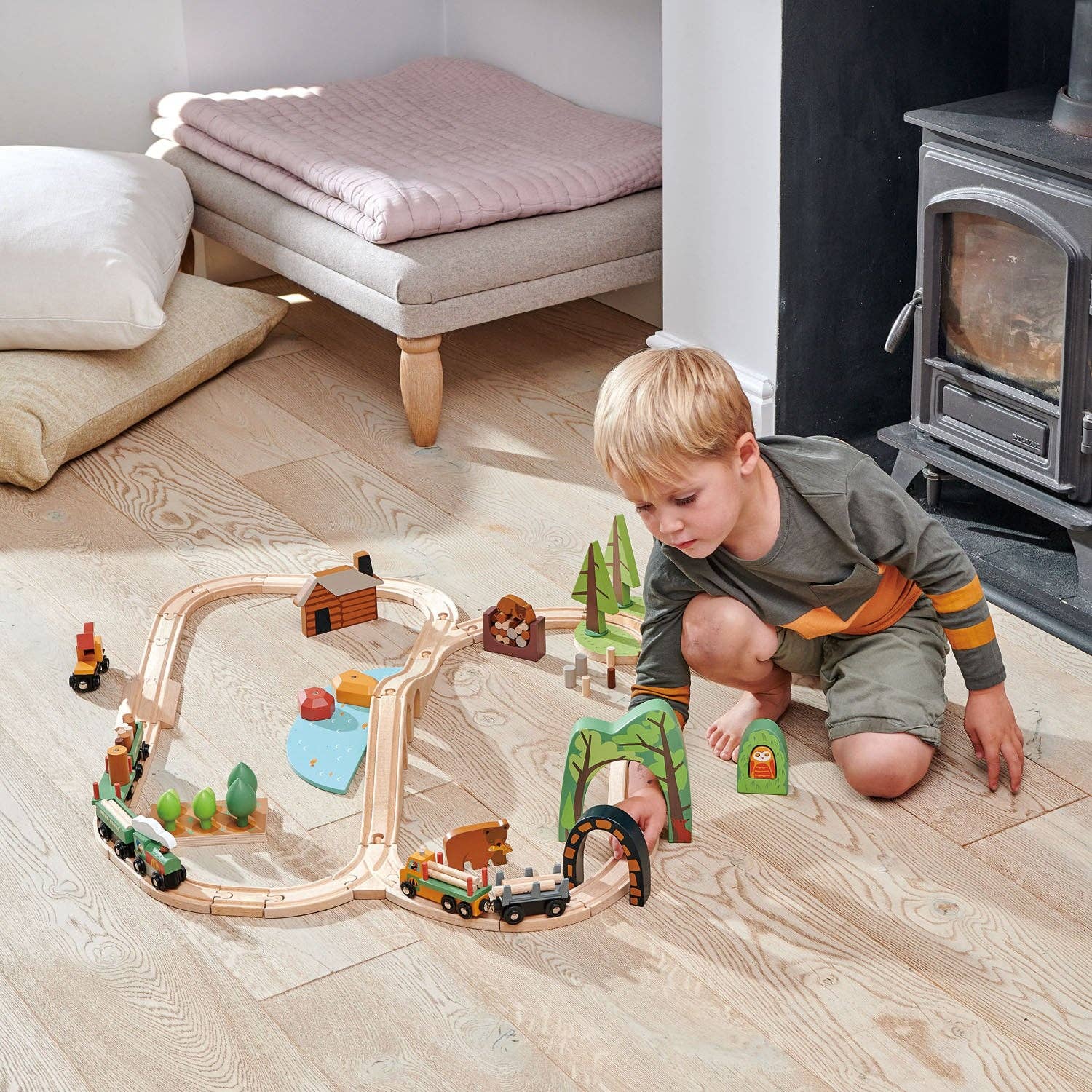 Child playing with a wooden train set on a wooden floor.