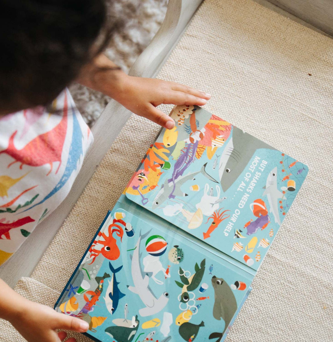 Child sat reading an illustrated book with pictures and words