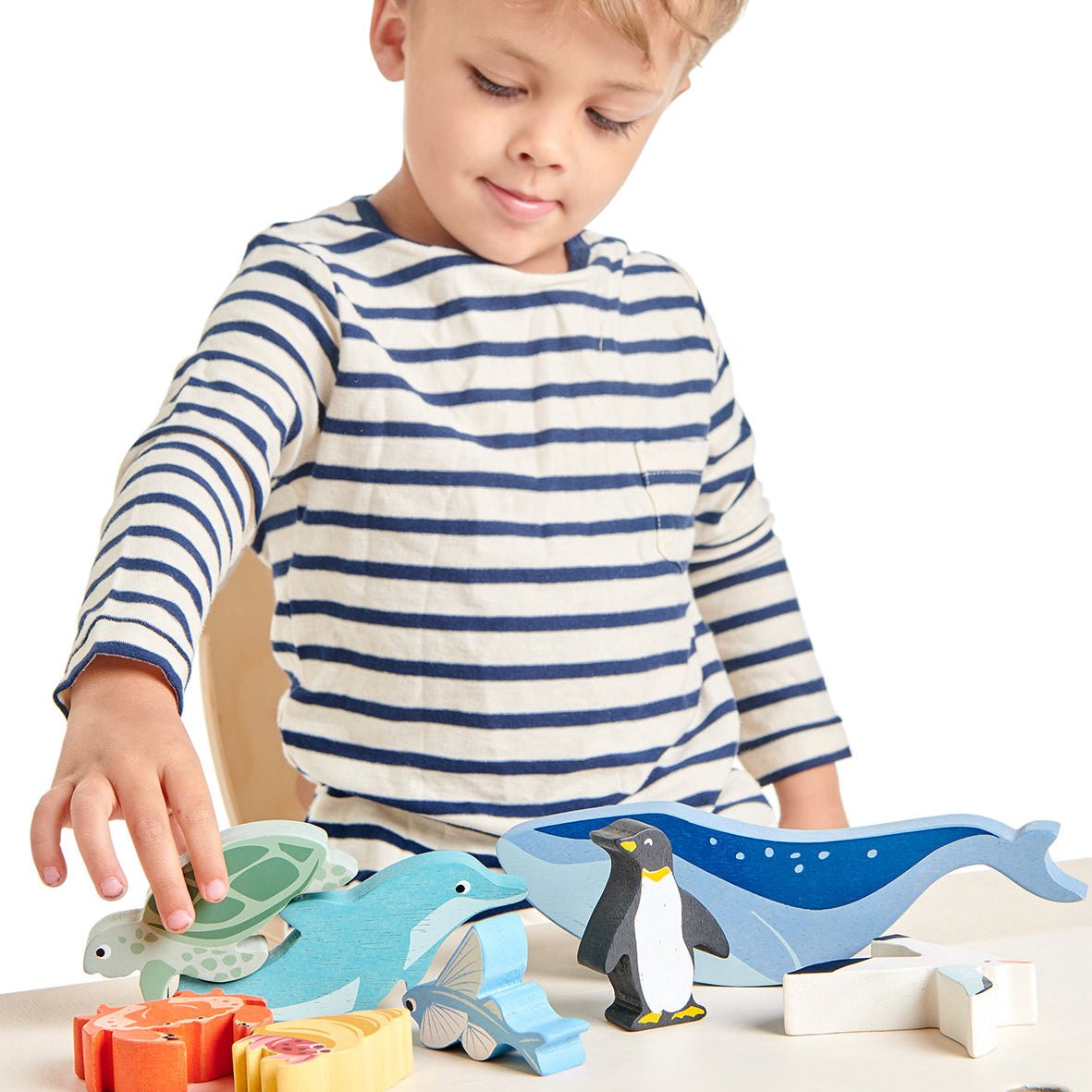 Child playing with wooden animal toys on a table