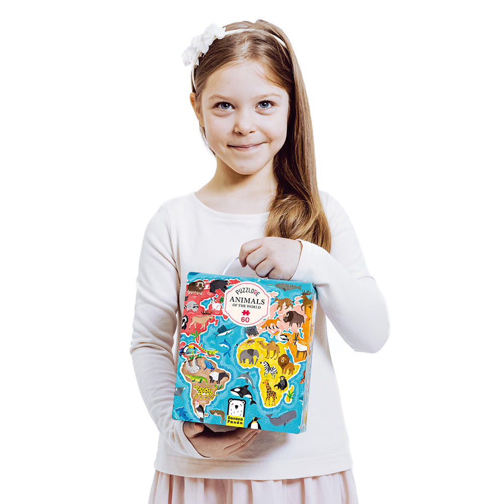 Young girl holding a colorful book titled 'Animals' against a white background
