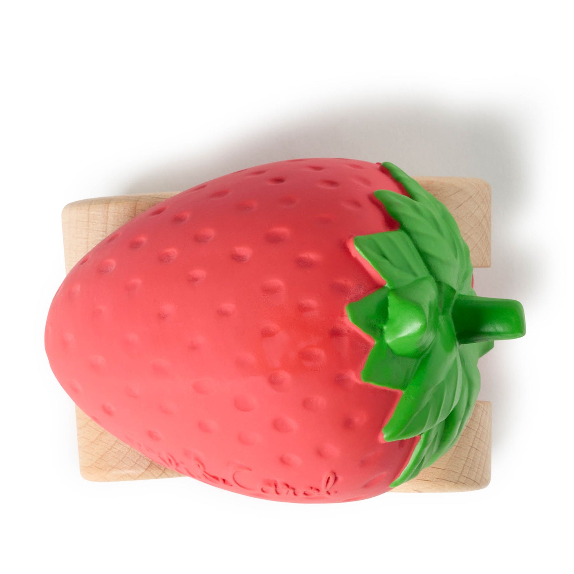 Strawberry-shaped object on a wooden cutting board with a white background