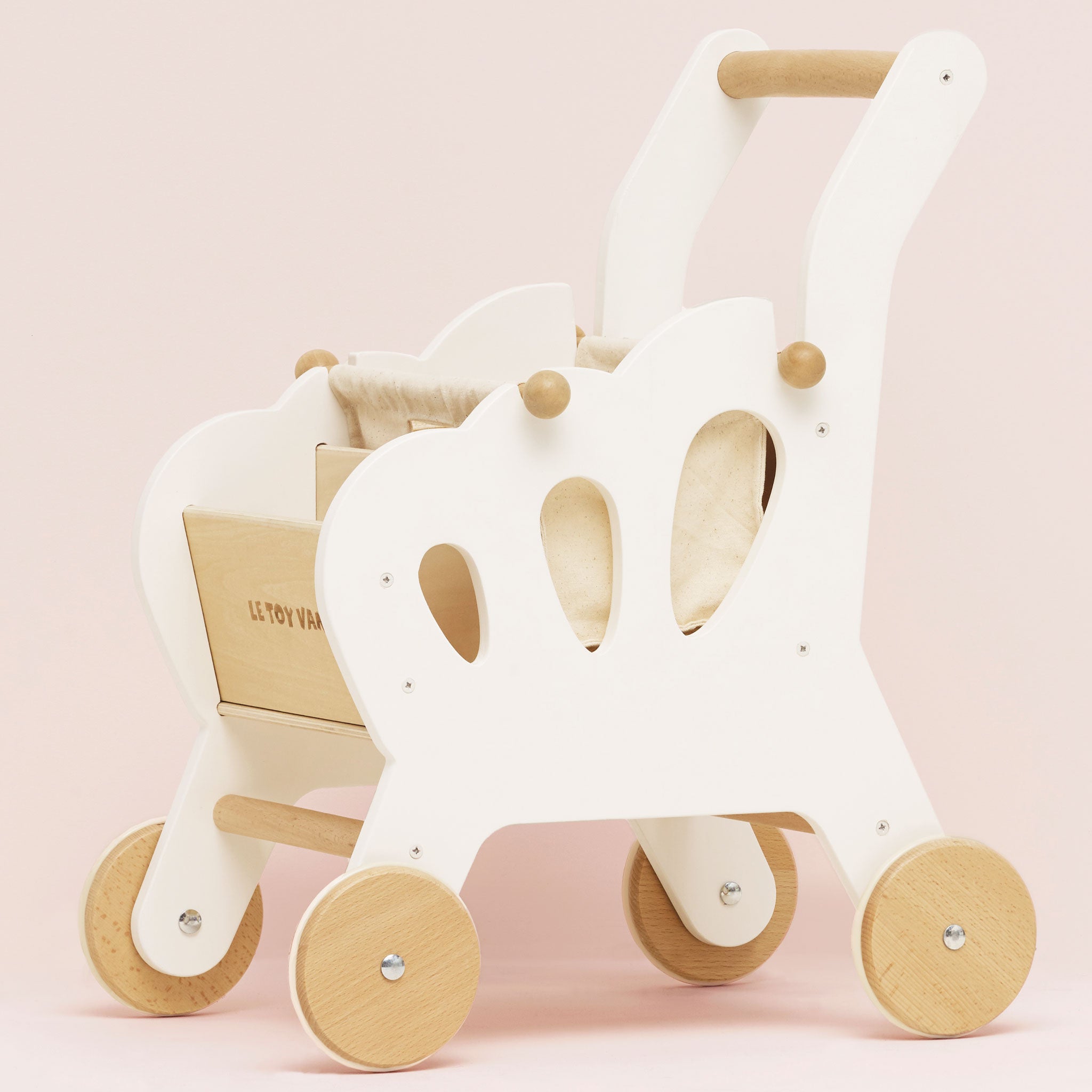 White and wooden children's push toy on a pink background