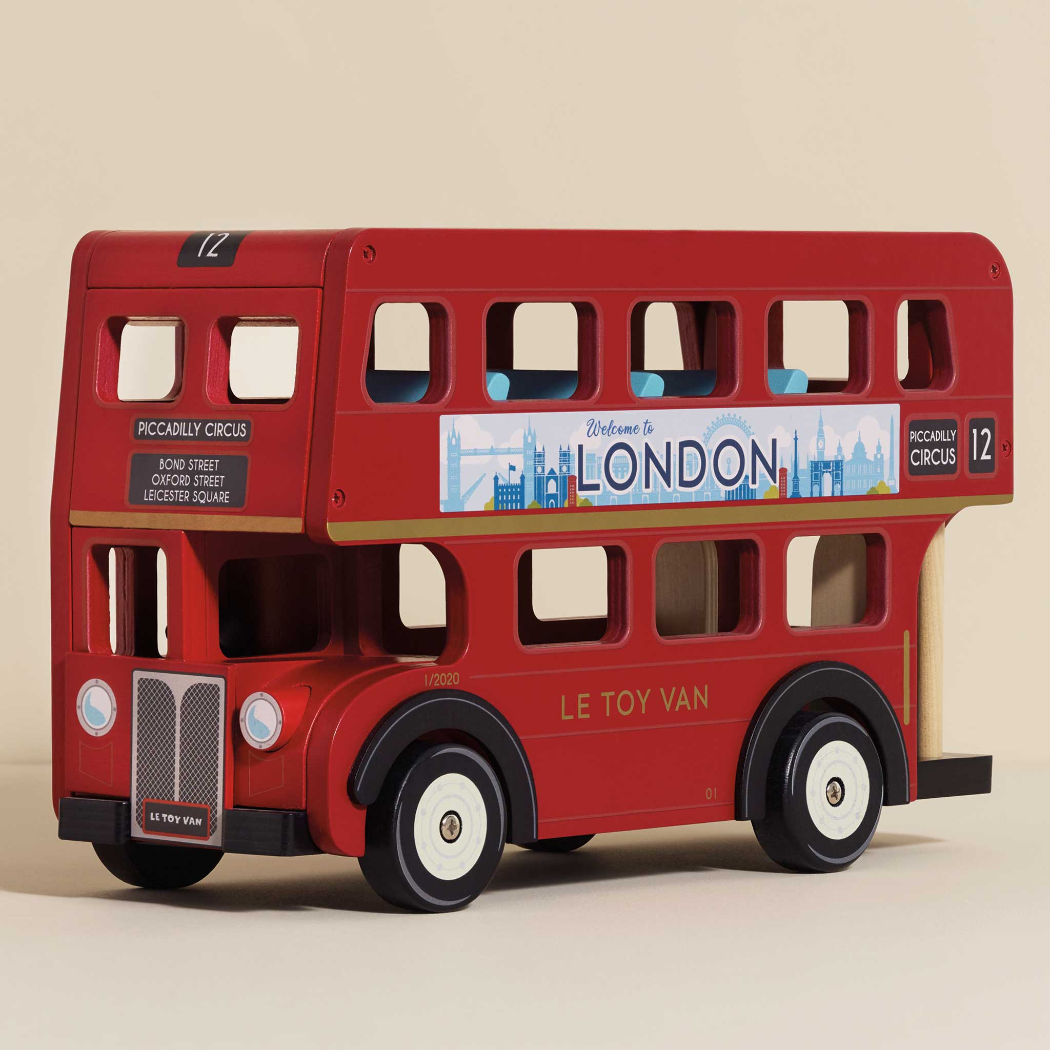 Red toy double-decker bus with 'Welcome to London' sign on a beige background