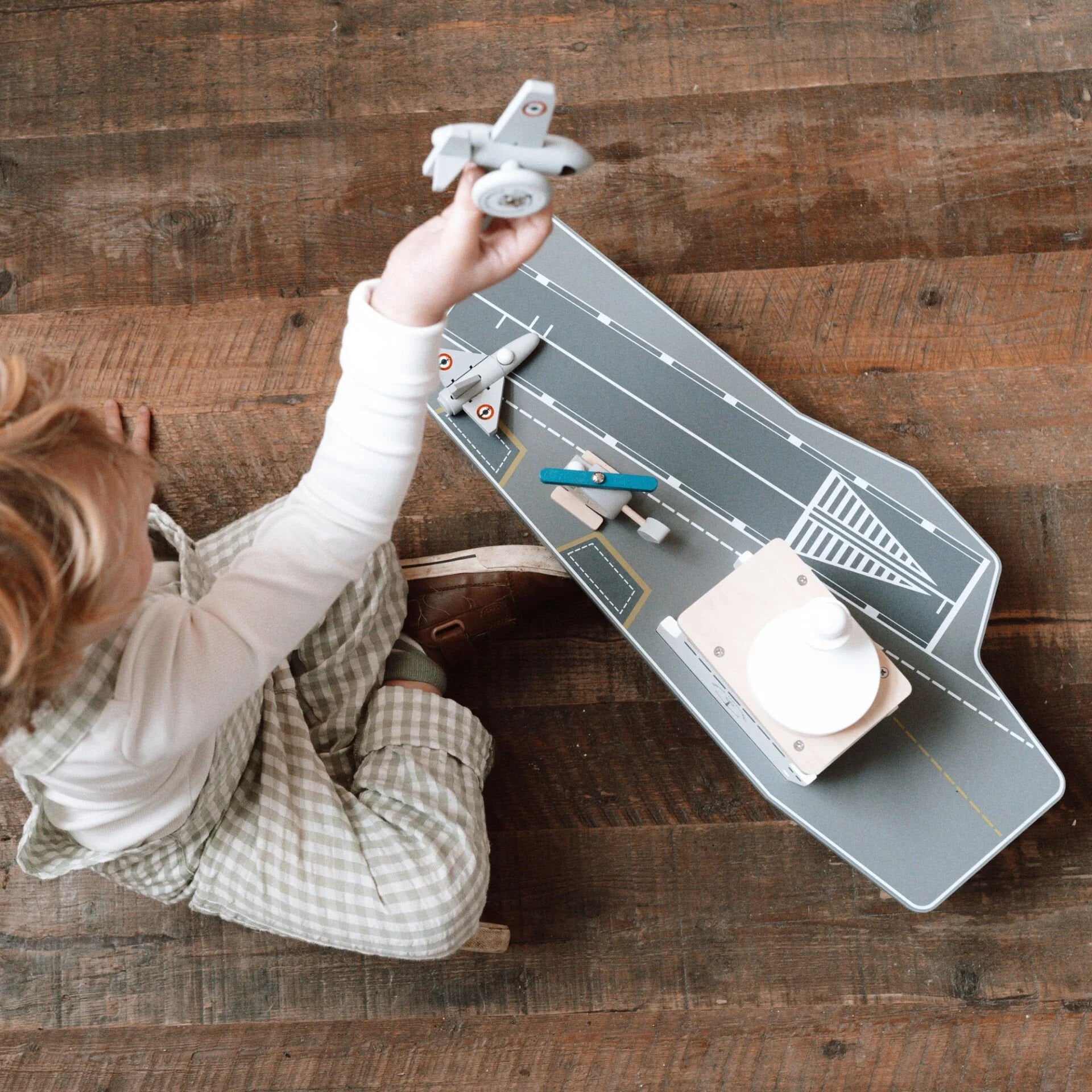 Child playing with toy airplanes on a wooden floor
