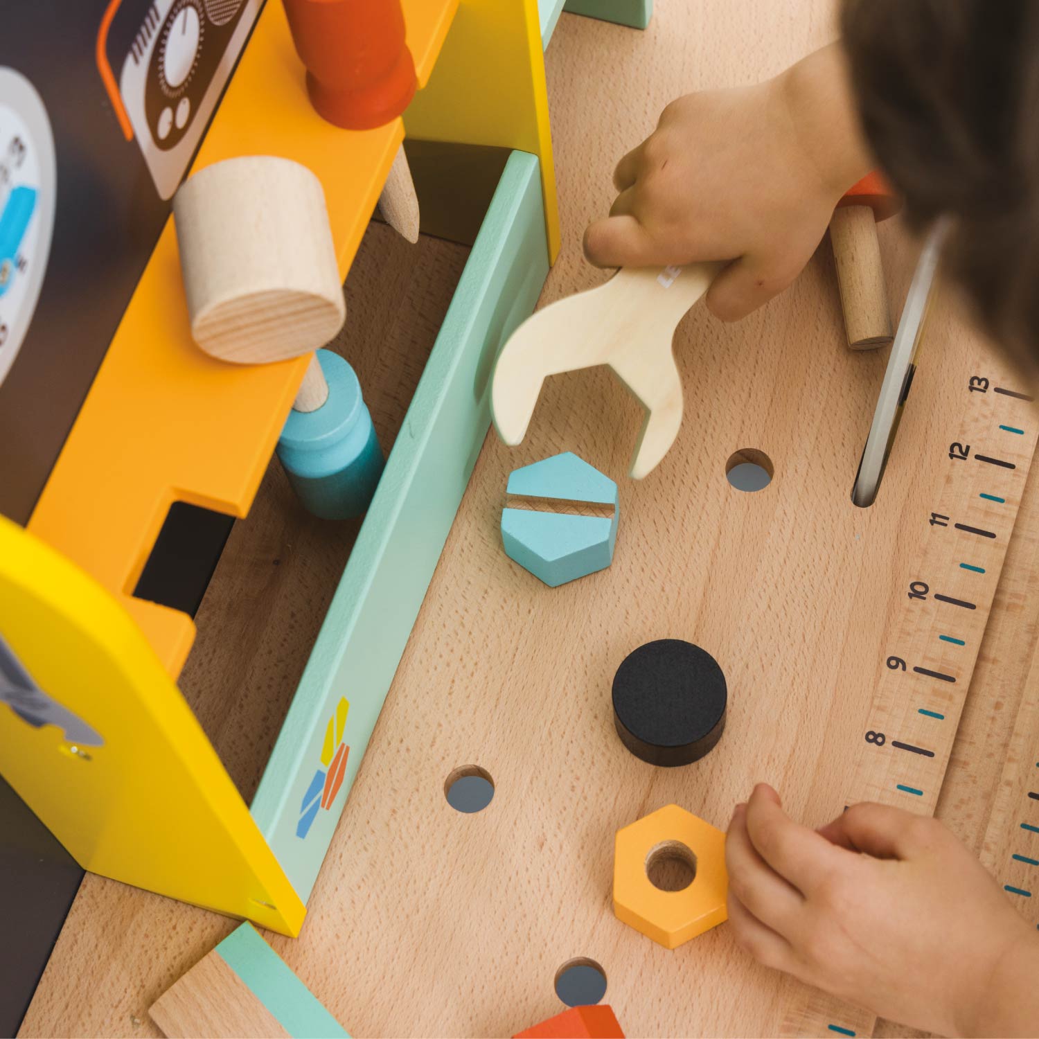 Child playing with toy tools and blocks on a wooden table