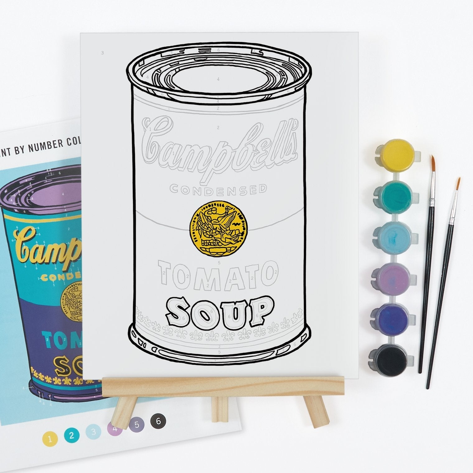 Coloring book page with a Campbell's Tomato Soup can design, watercolor paints, and brushes on a white background.