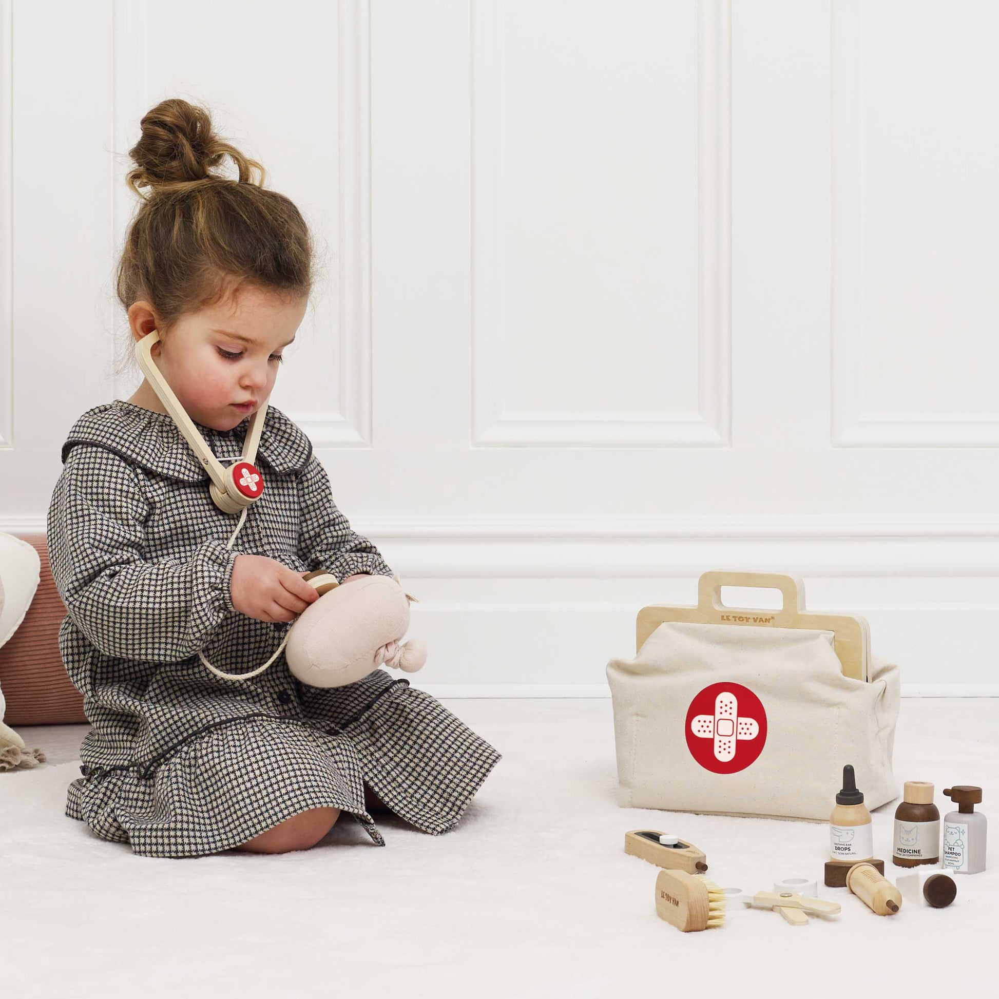 Child playing with a toy medical kit on a white floor.