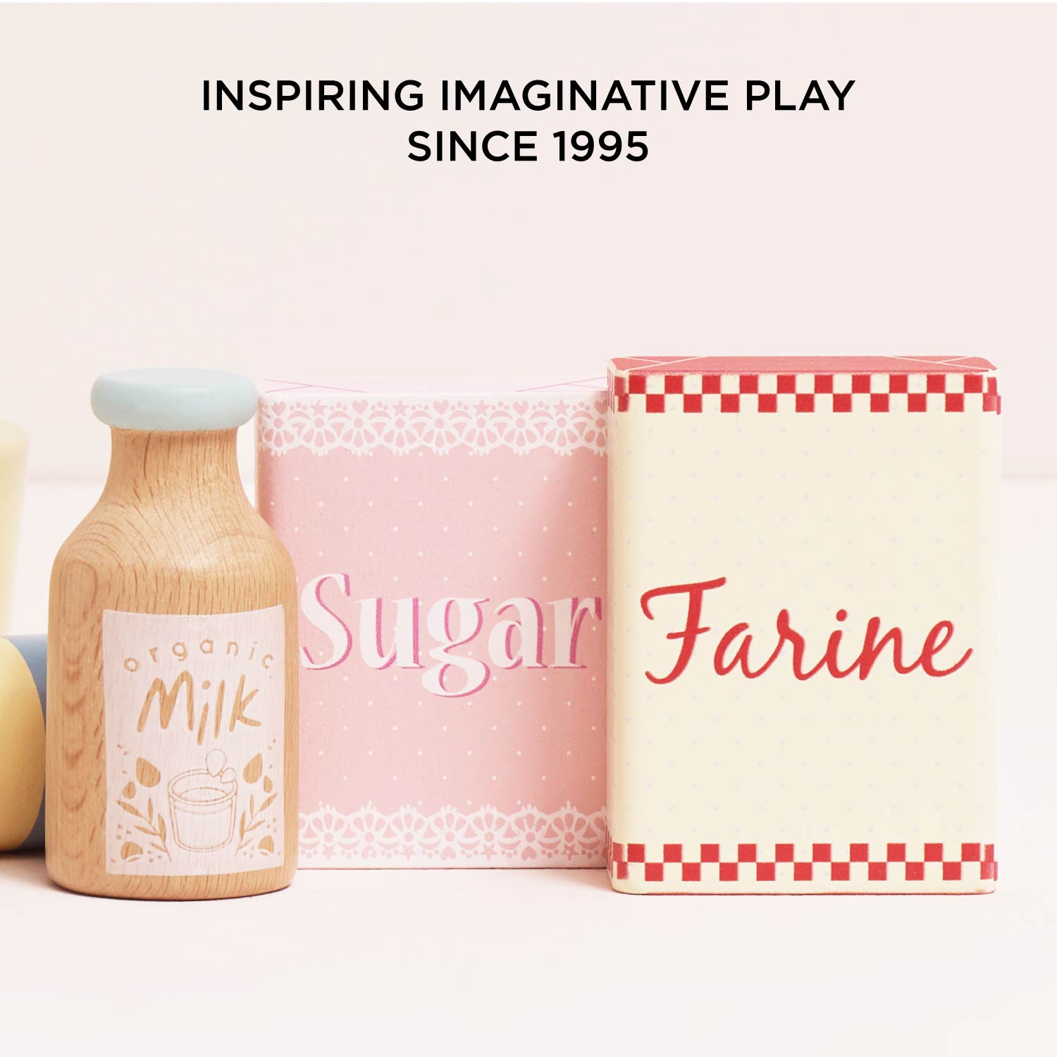 Toy milk bottle, sugar container, and flour container with 'Inspiring Imaginative Play Since 1995' text.