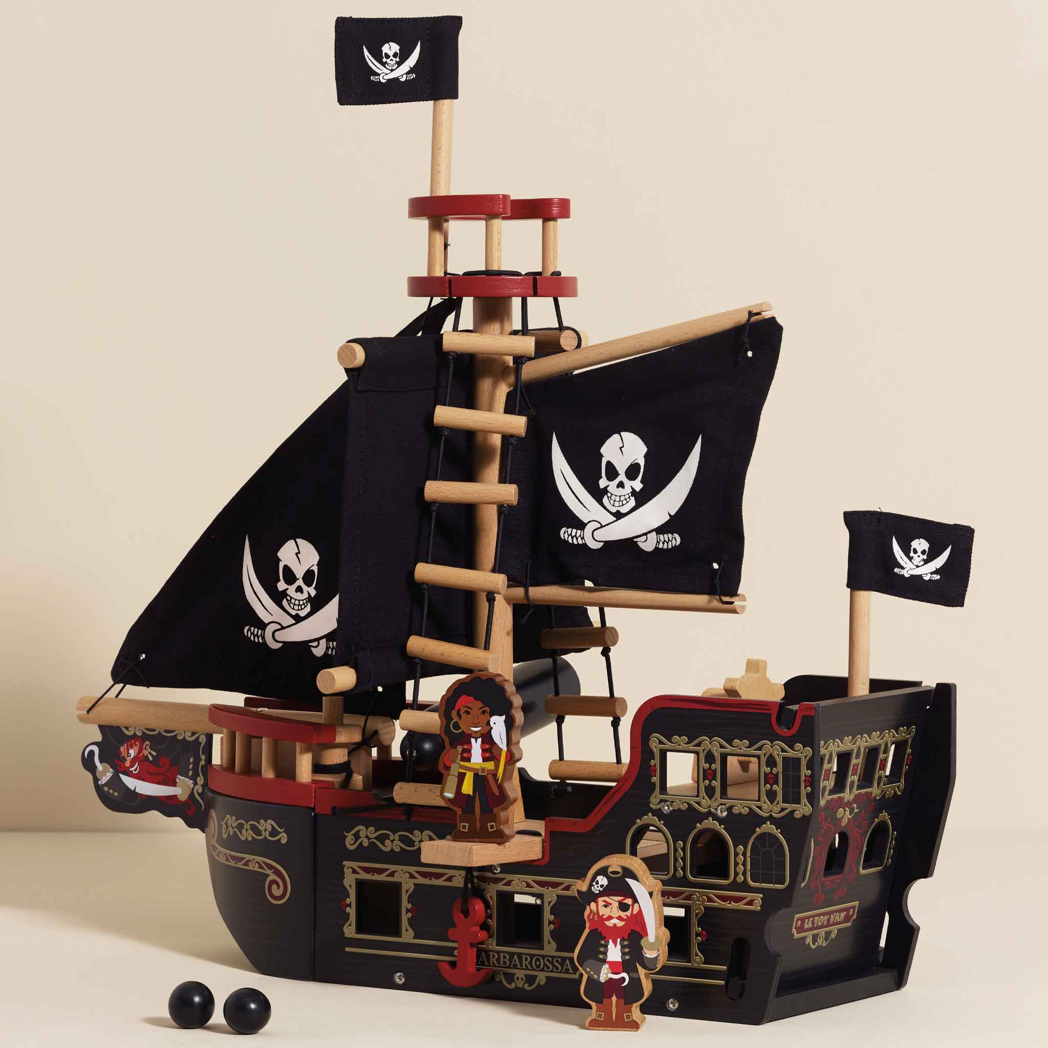 Toy pirate ship with black sails and skull designs on a beige background