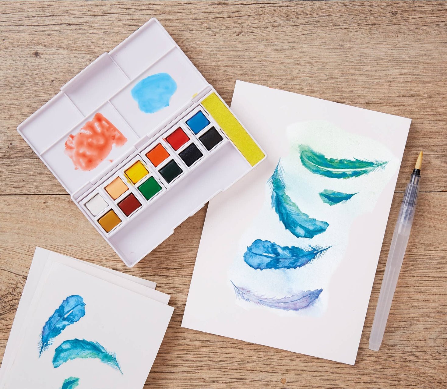 Watercolor set with painted feathers on paper