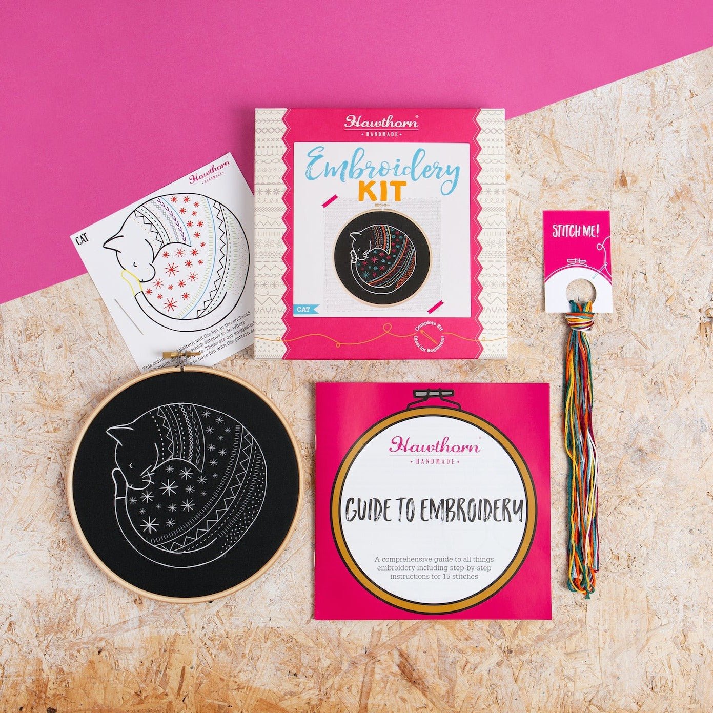 Embroidery kit with hoop, pattern, and guide on a textured surface with pink background