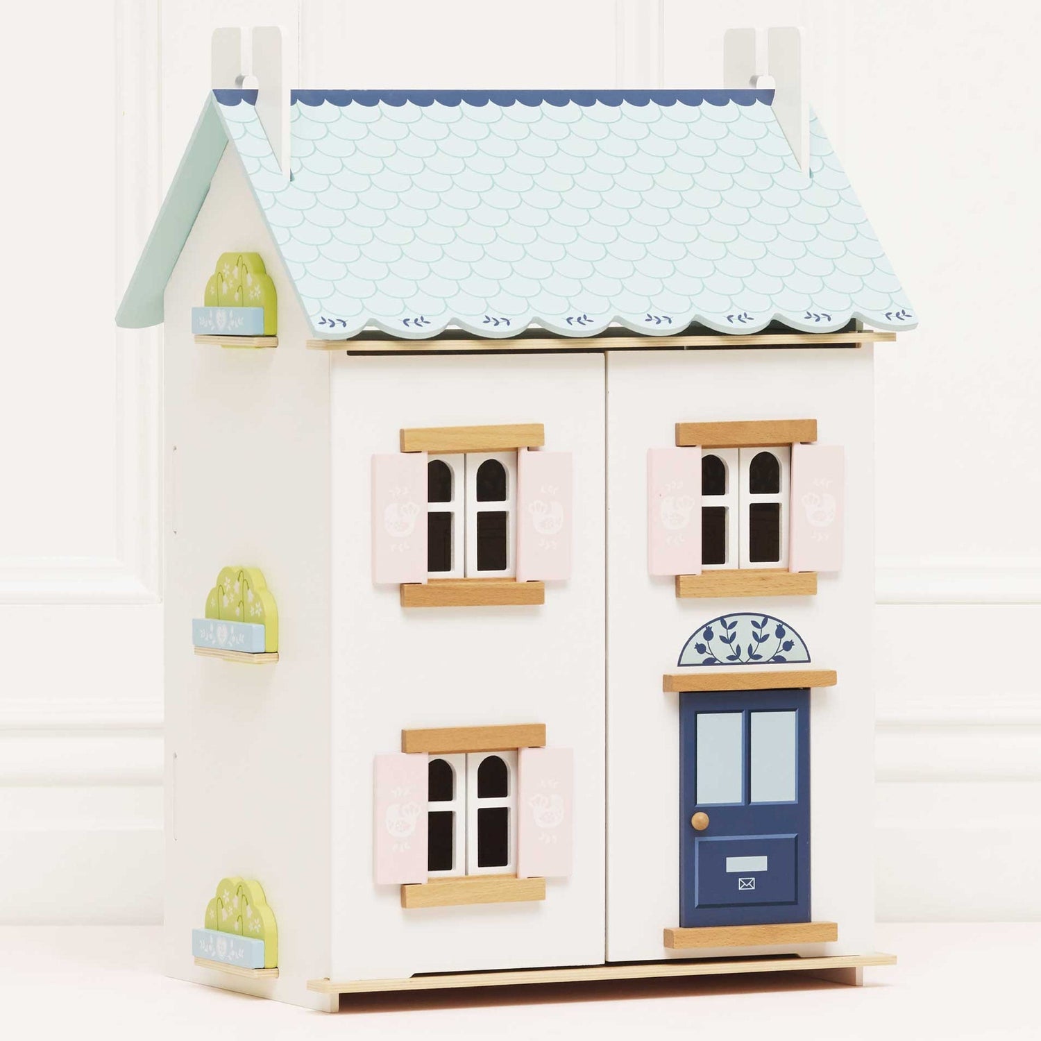Wooden dollhouse with pastel colors on a white background