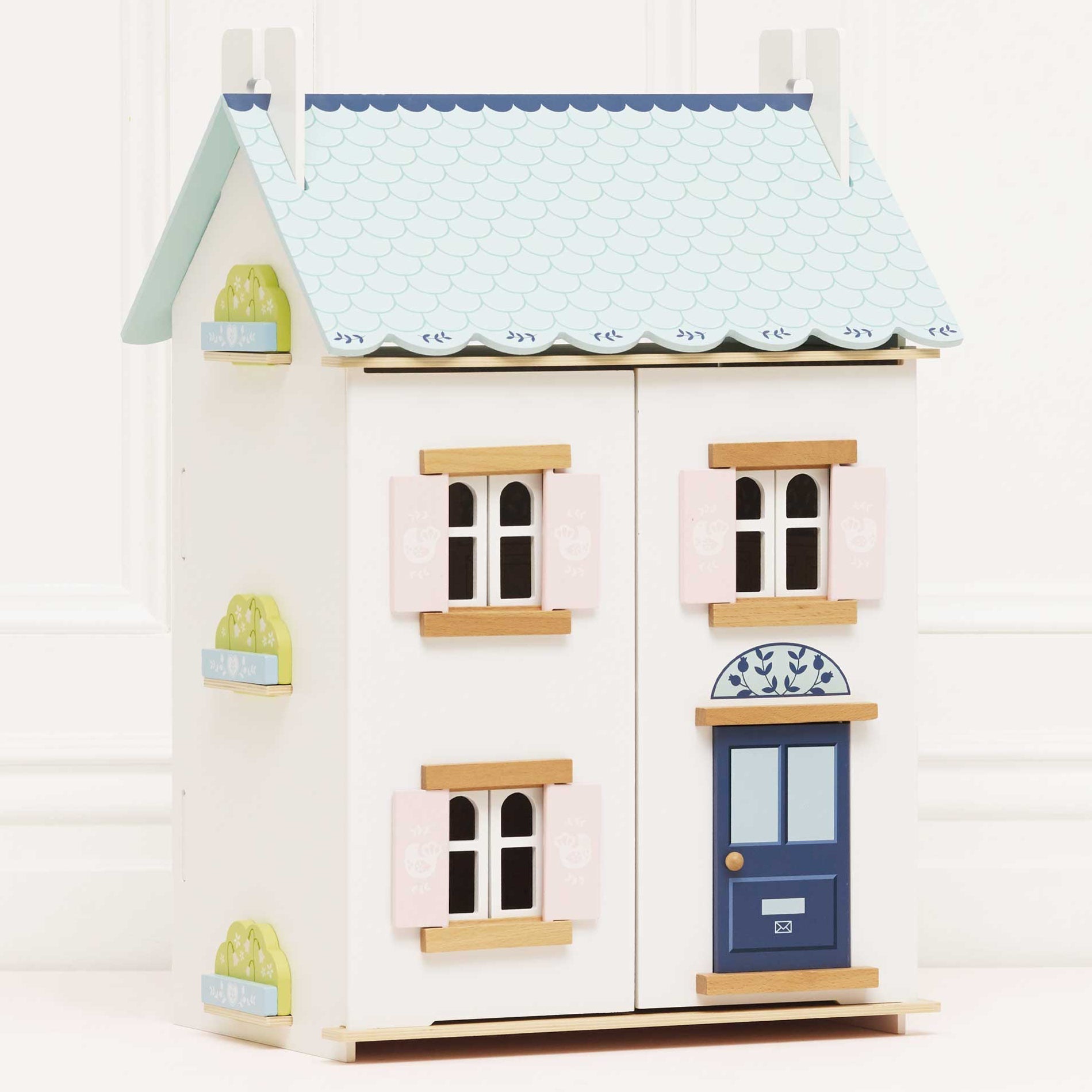 Wooden dollhouse with pastel colors on a white background