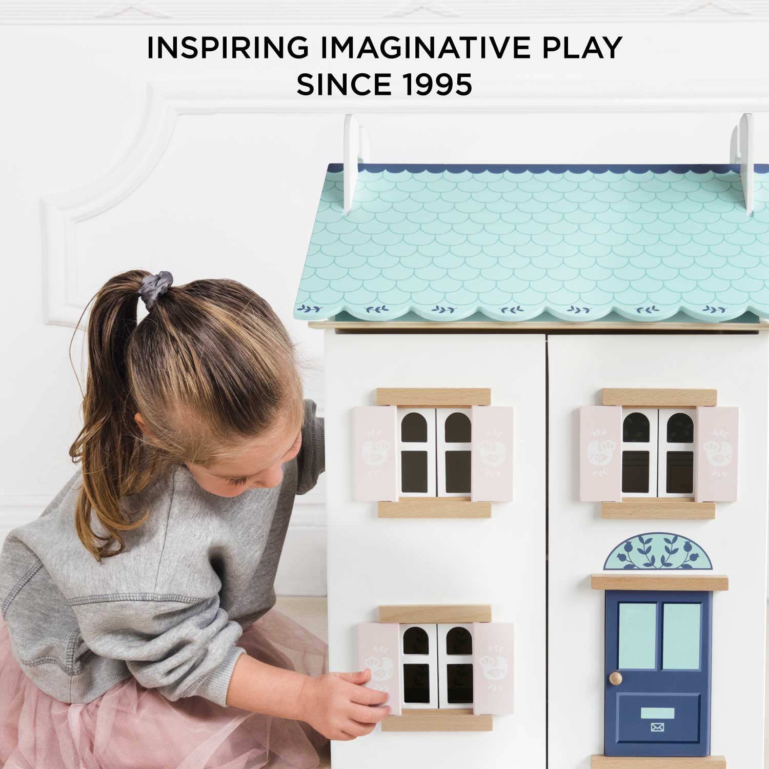 Child playing with a toy house, inspired by imaginative play since 1995