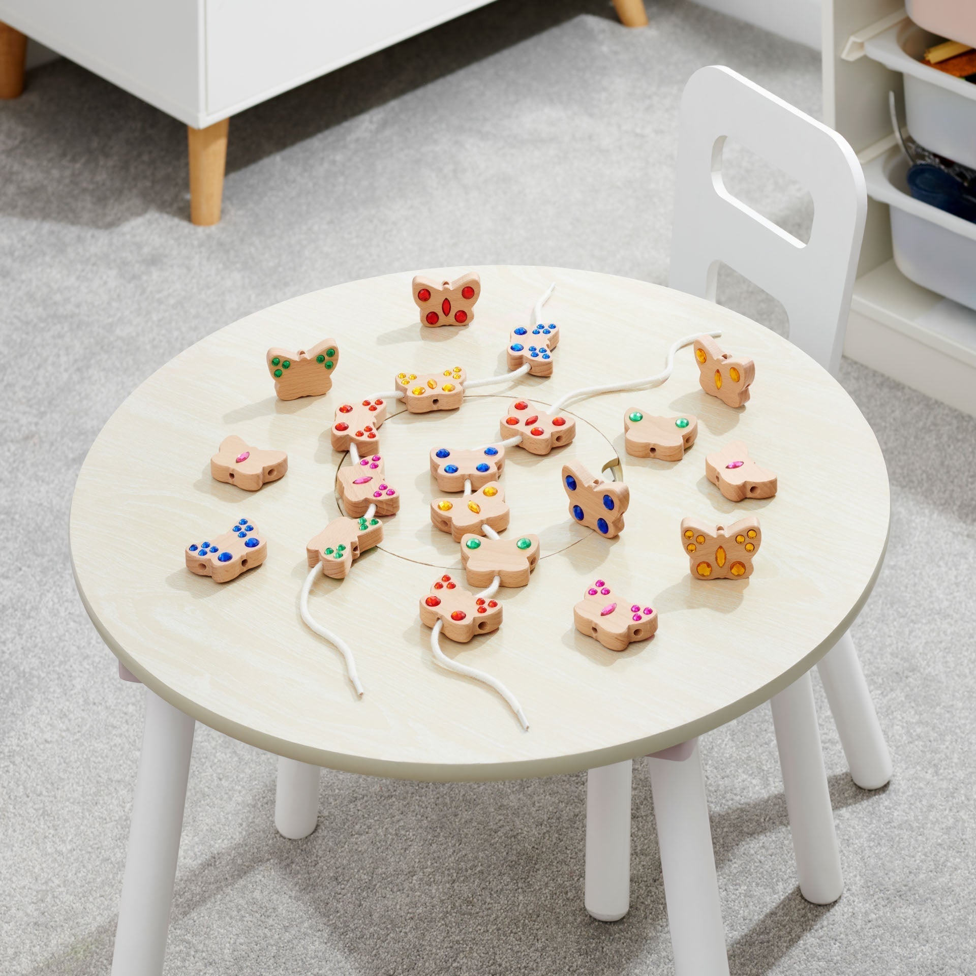 Round white table with wooden toys on a gray carpeted floor