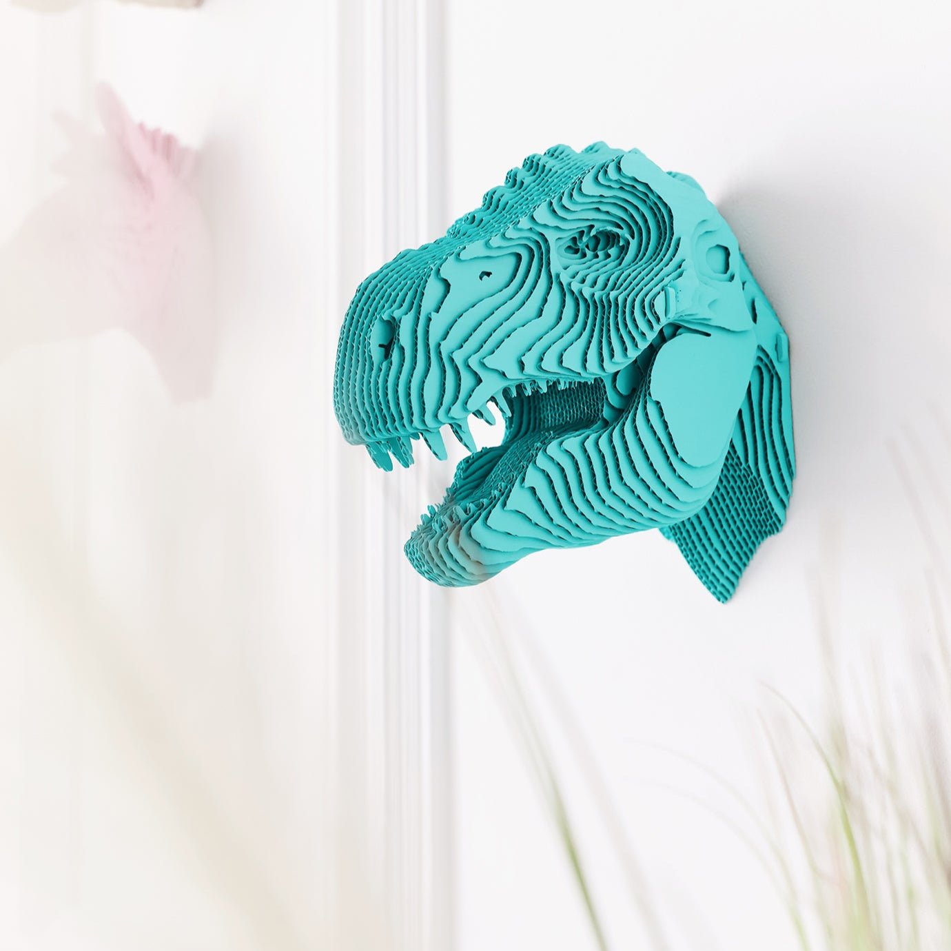 Turquoise dinosaur head wall decoration on a white background