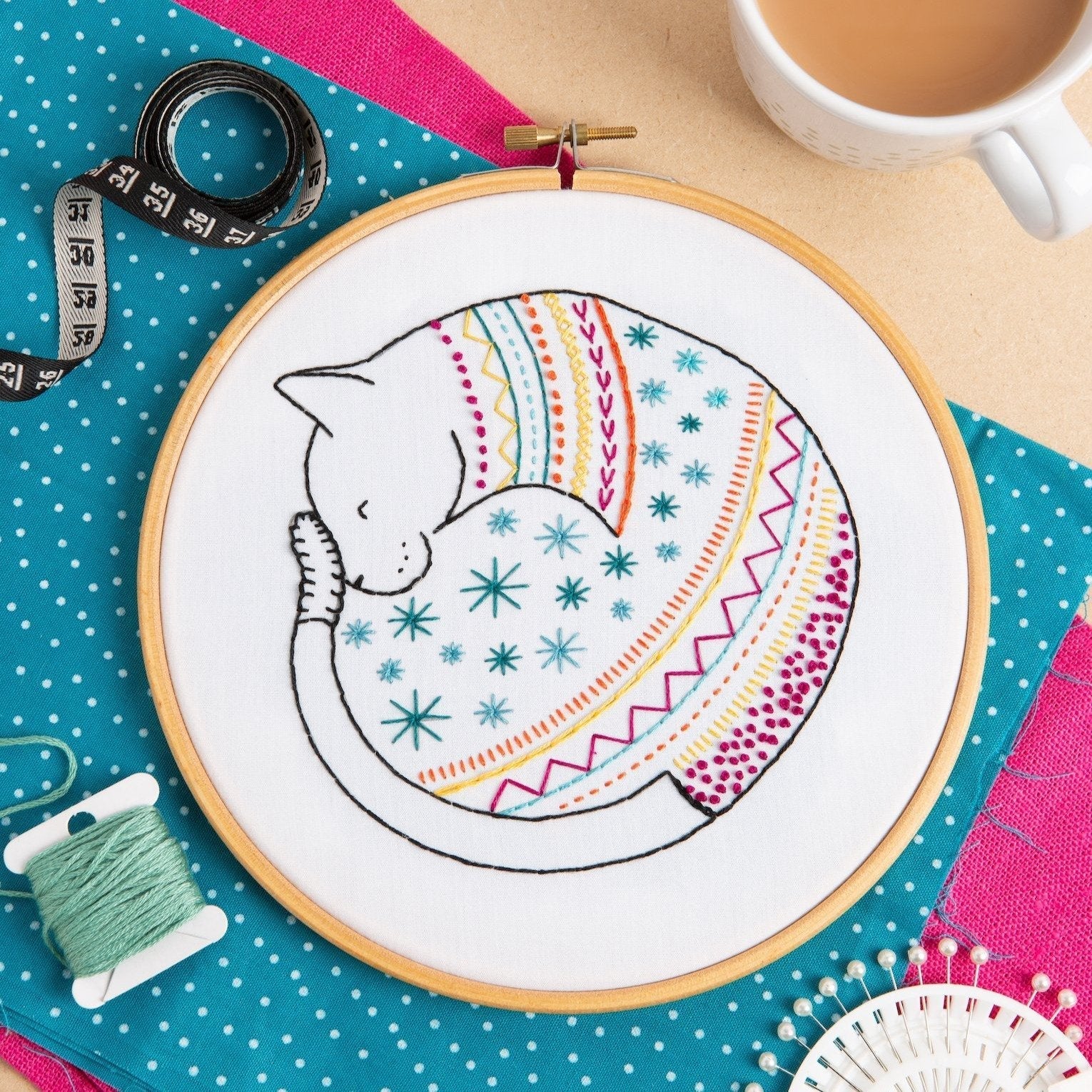 Embroidery hoop with a colorful cat design on a polka dot fabric background.