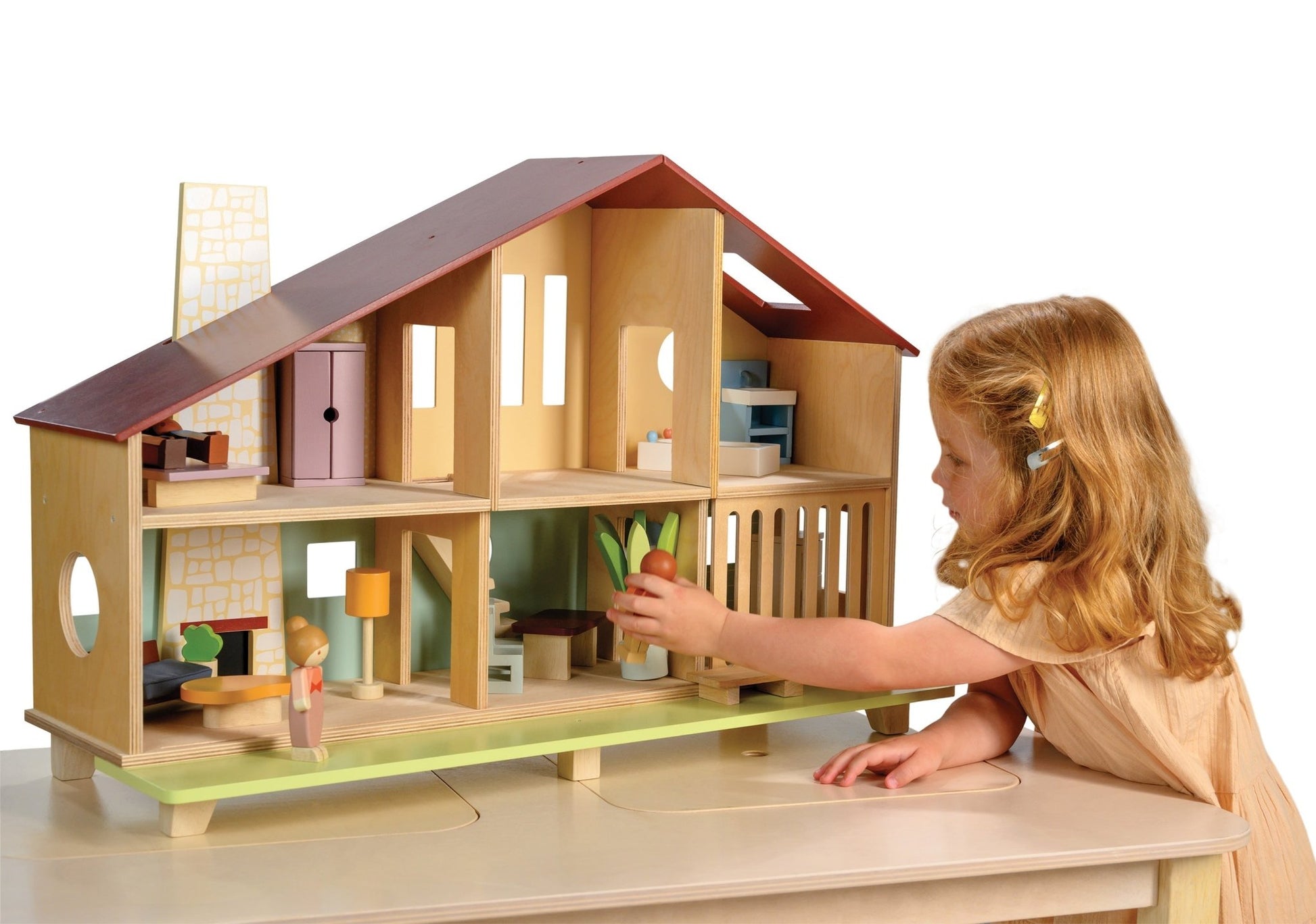 Child playing with a wooden dollhouse on a white background