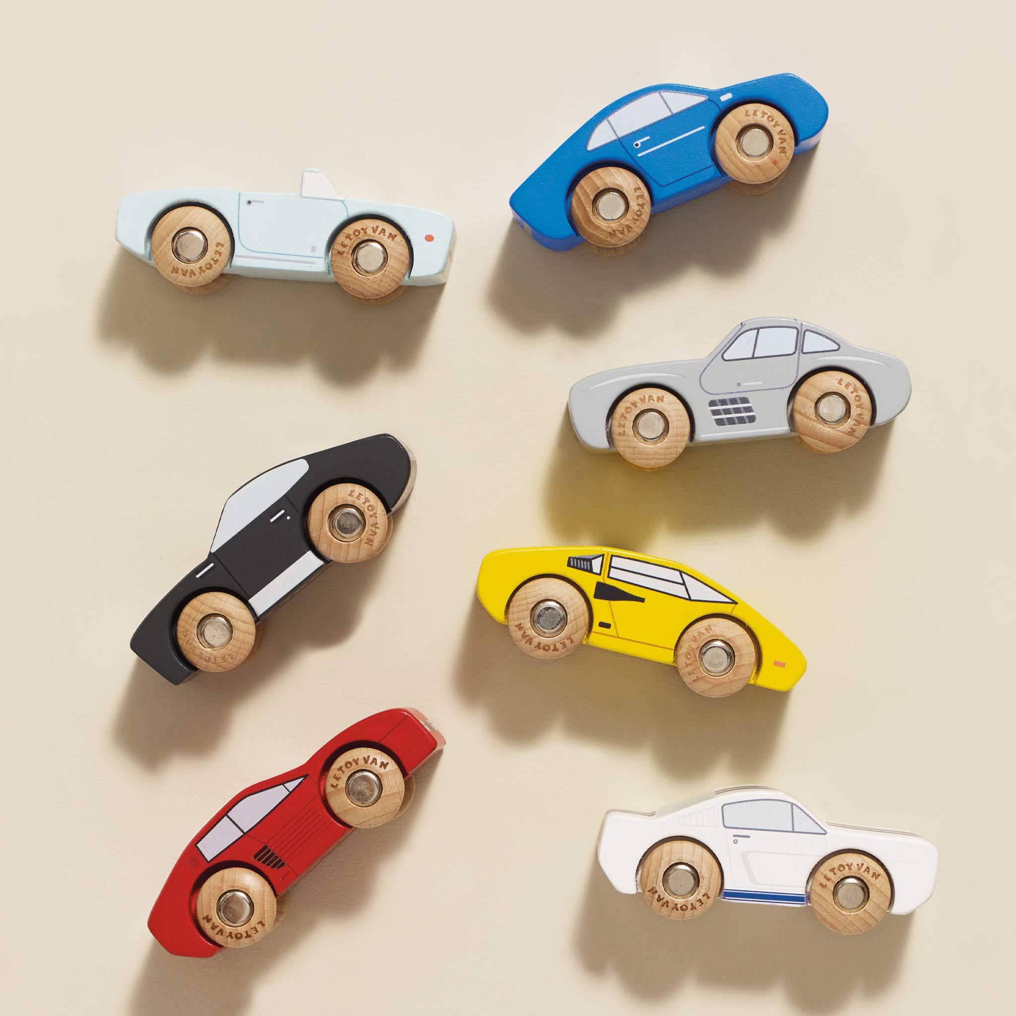 Set of colorful wooden toy cars on a beige background