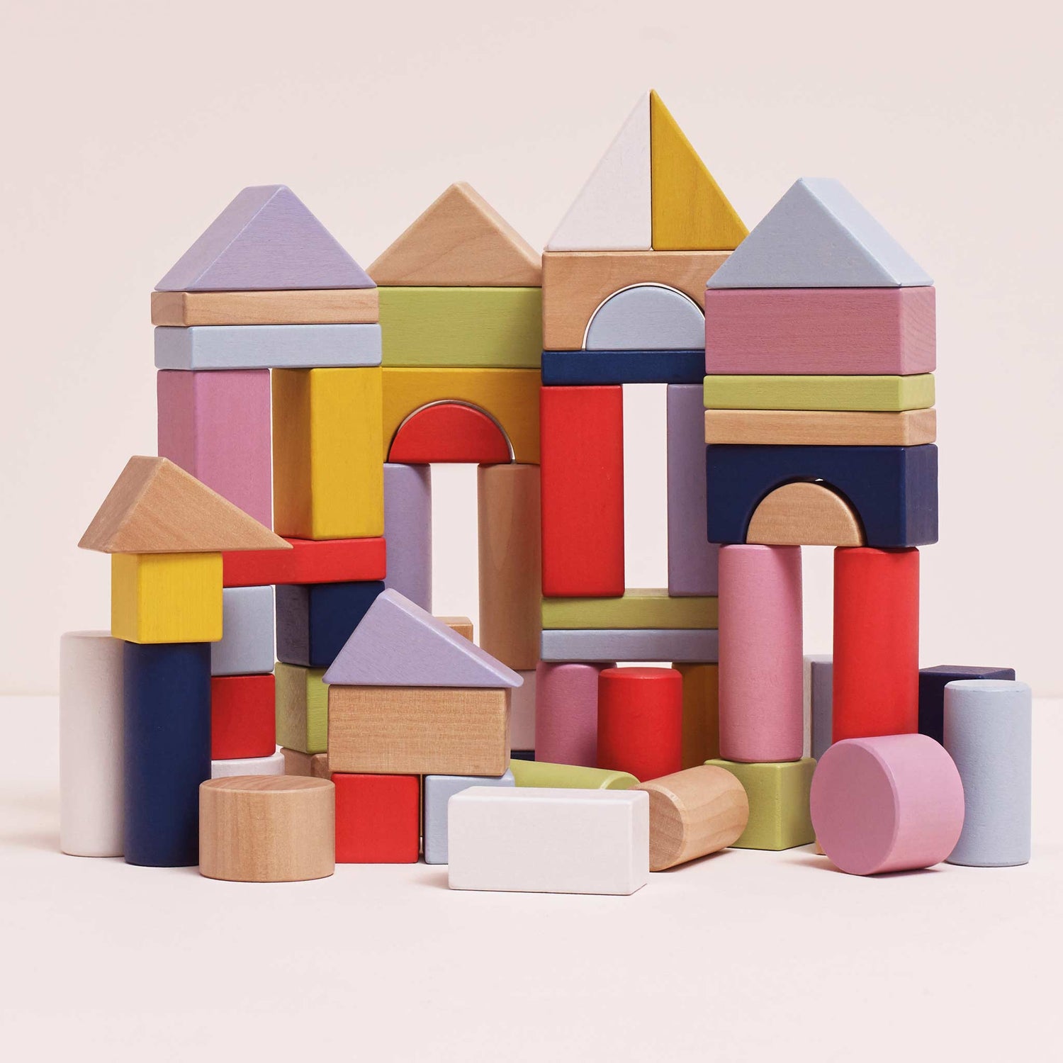 Colorful wooden building blocks on a light pink background