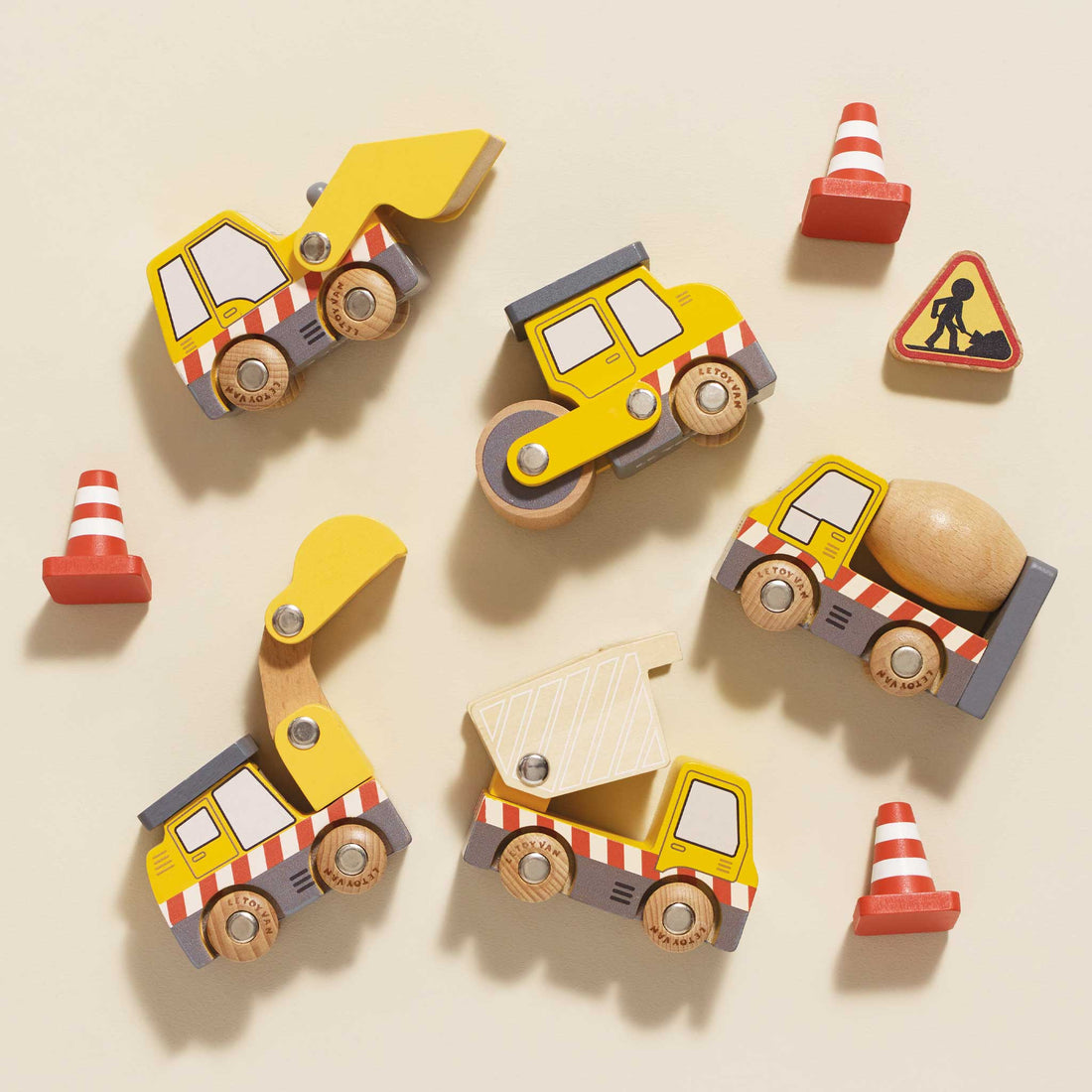 Set of wooden toy construction vehicles on a beige background