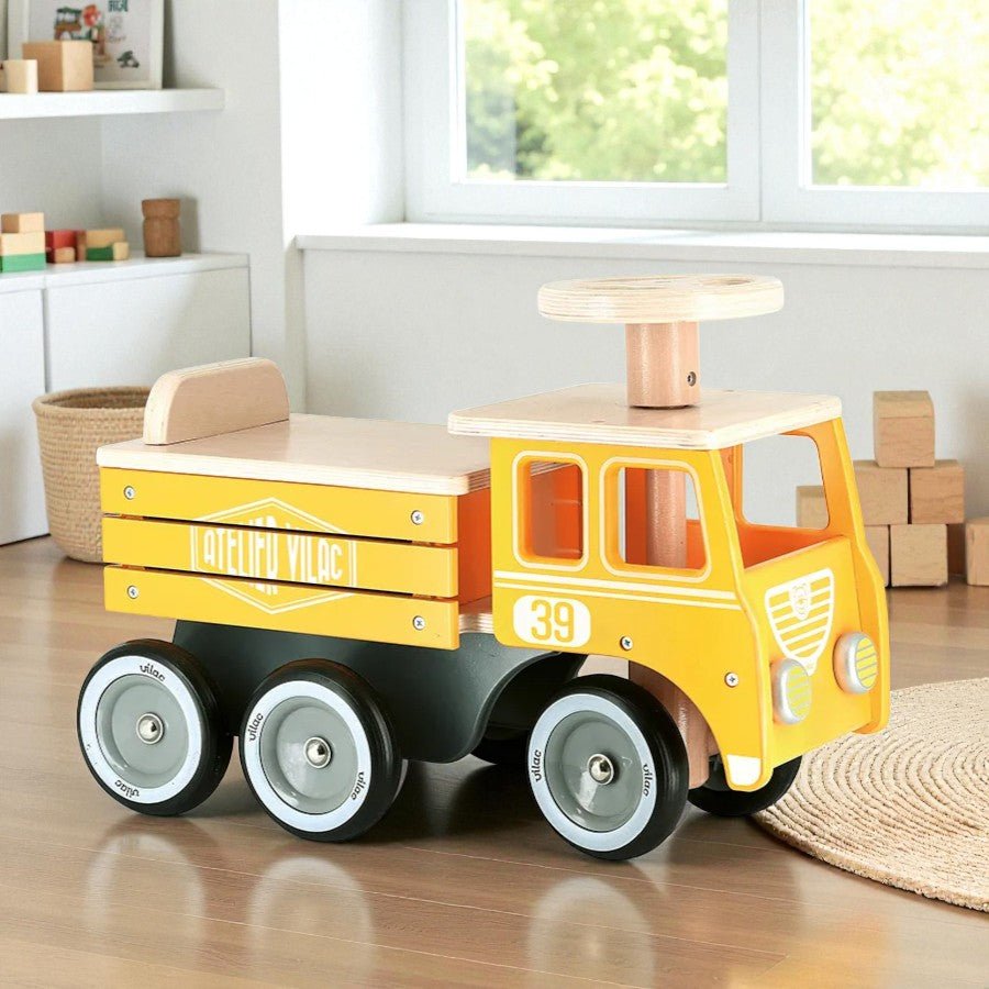 Yellow toy truck with wooden top on a wooden floor
