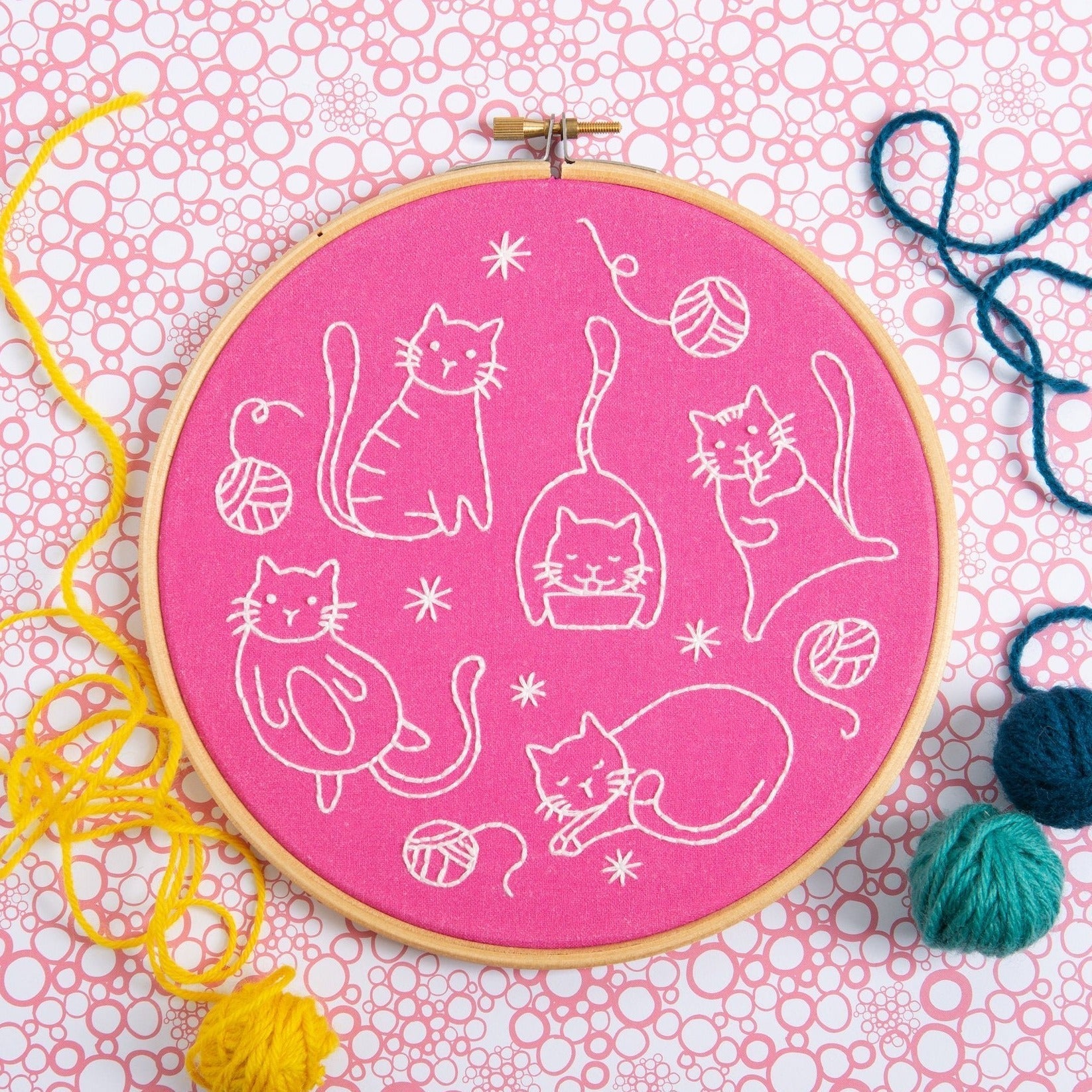 Embroidery hoop with cat patterns on a pink background
