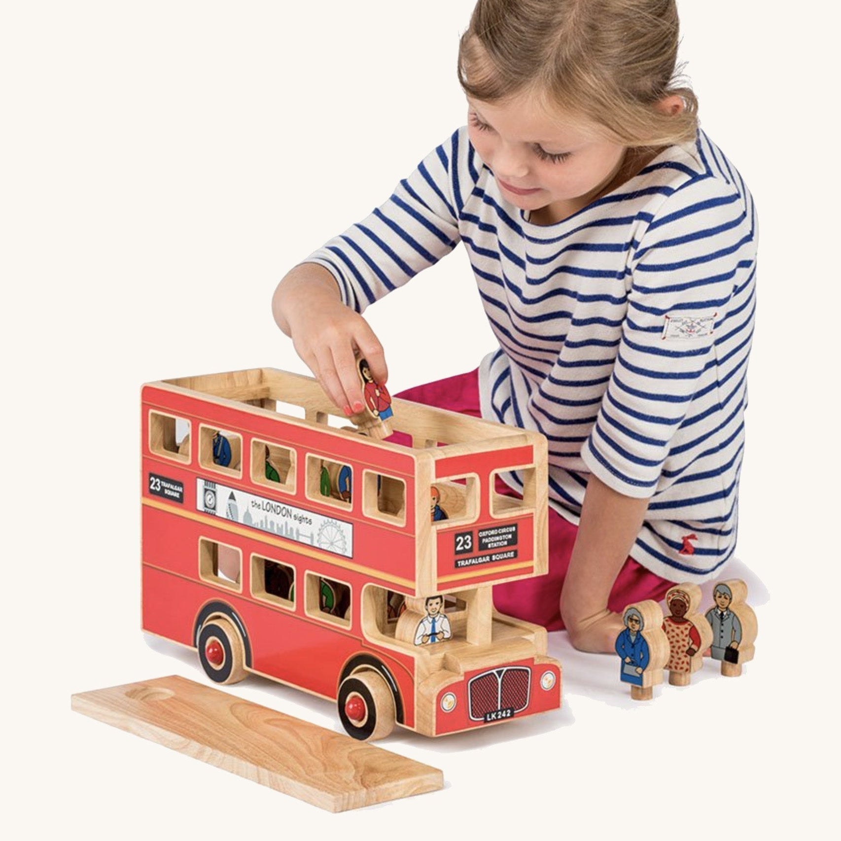 Child playing with a wooden toy bus on a white background
