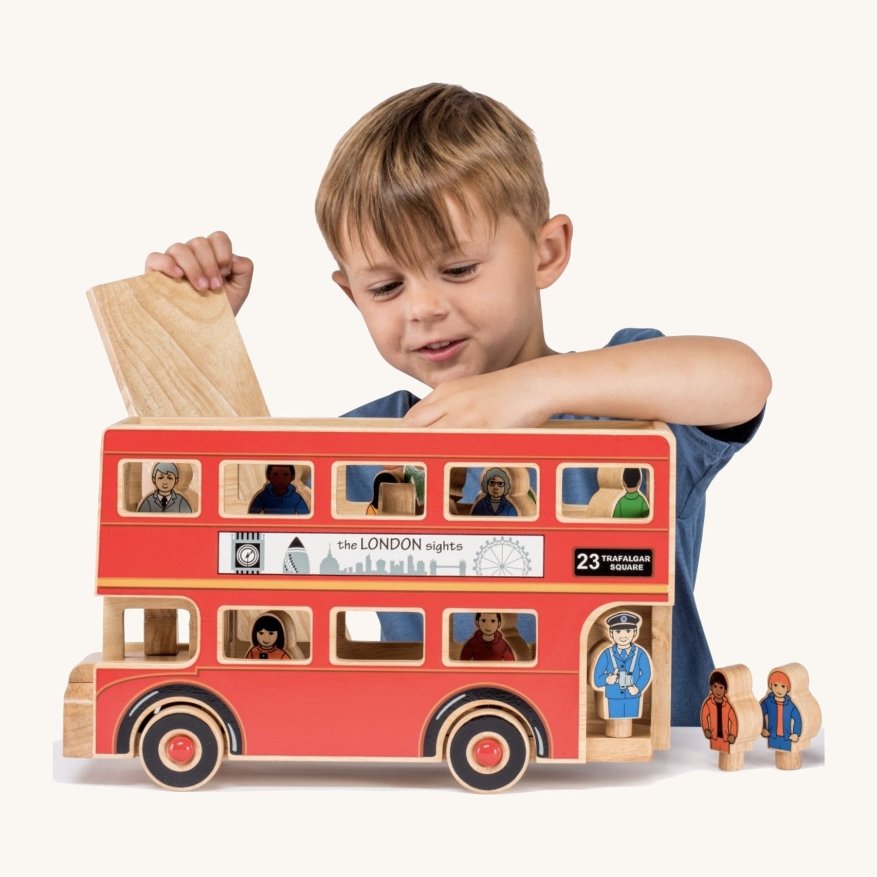 Child playing with a wooden toy bus and figures on a white background