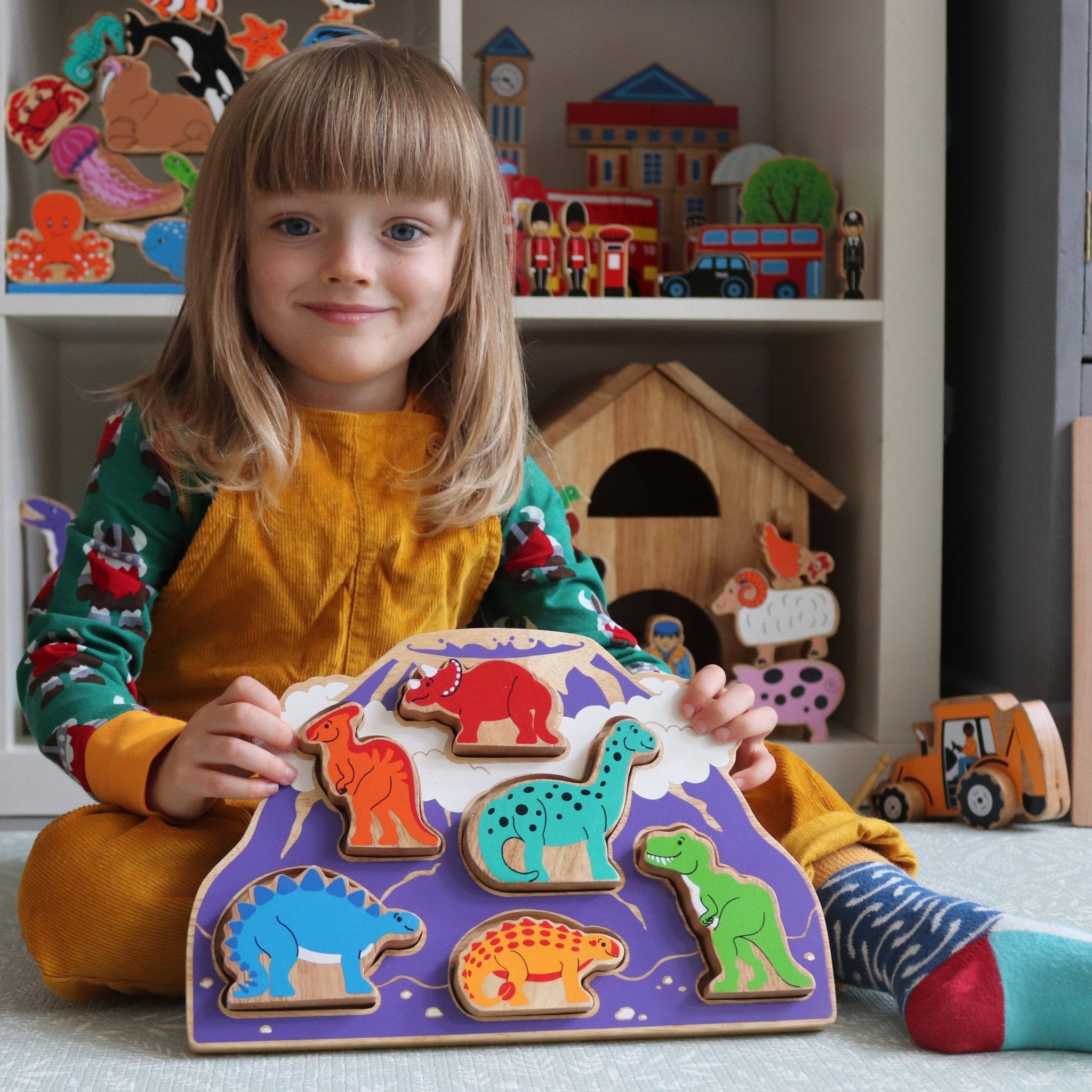 Child playing with a dinosaur puzzle in a room filled with toys