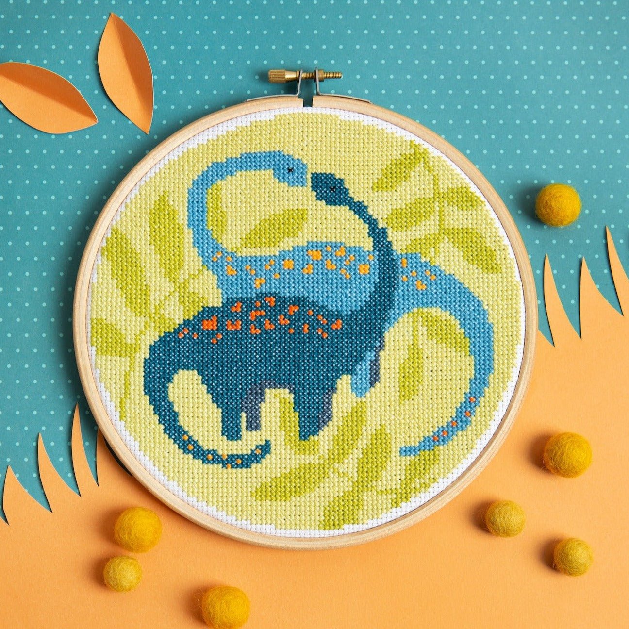 Embroidery hoop with a blue dinosaur design on a colorful background