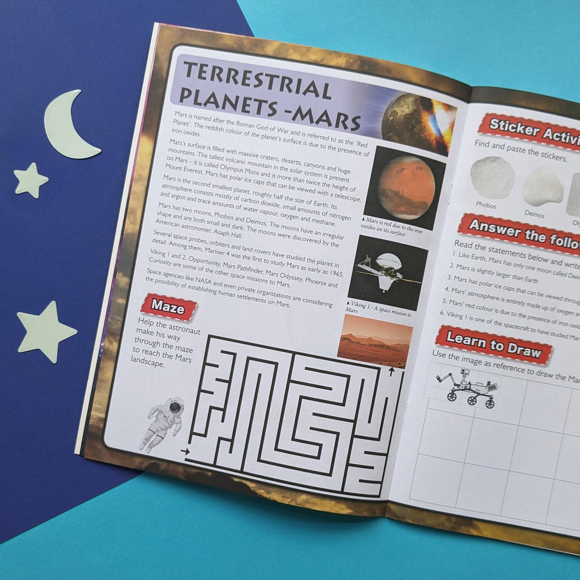 Educational book open to pages about Mars with a maze and sticker activity on a blue background.