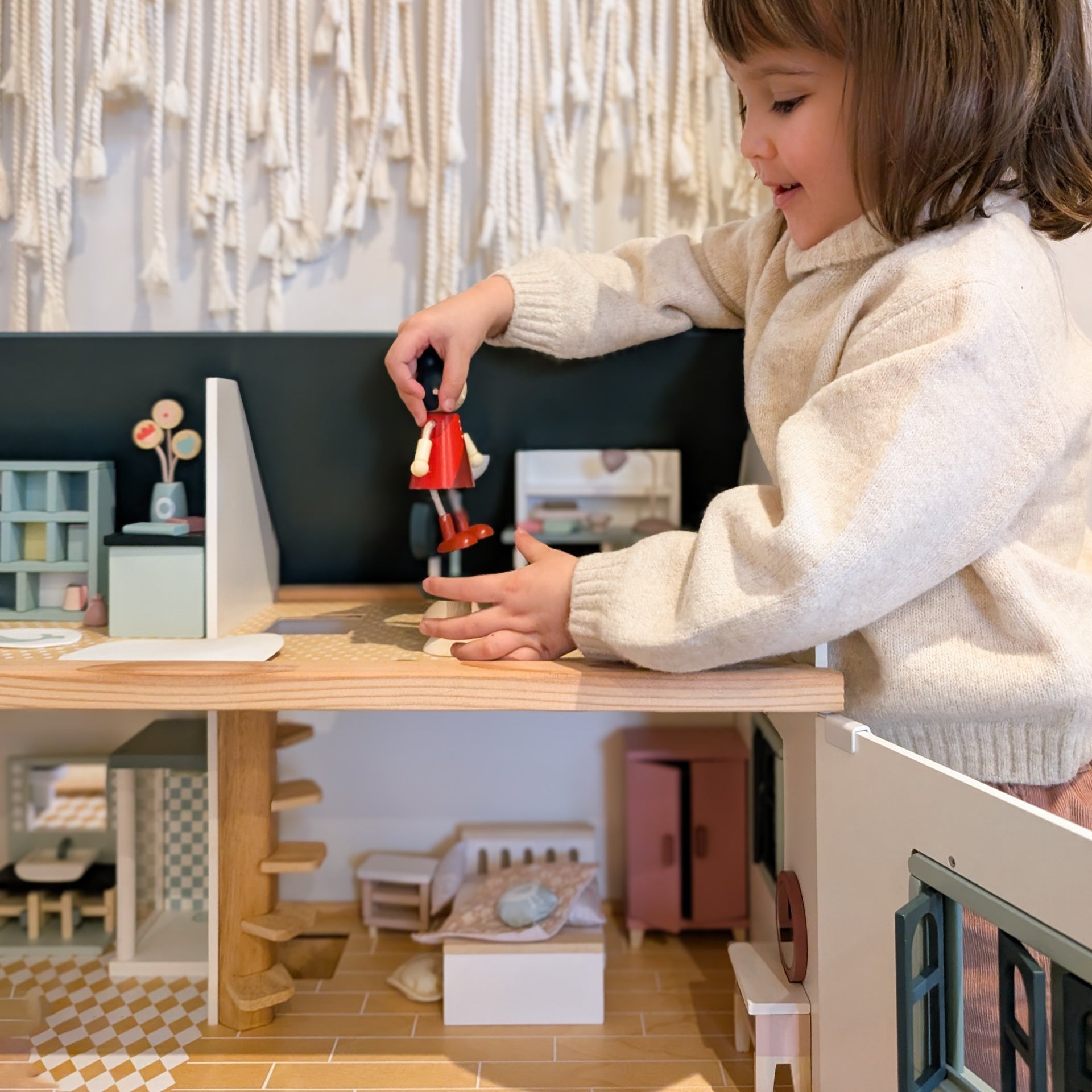 Child playing with a toy in a dollhouse setup