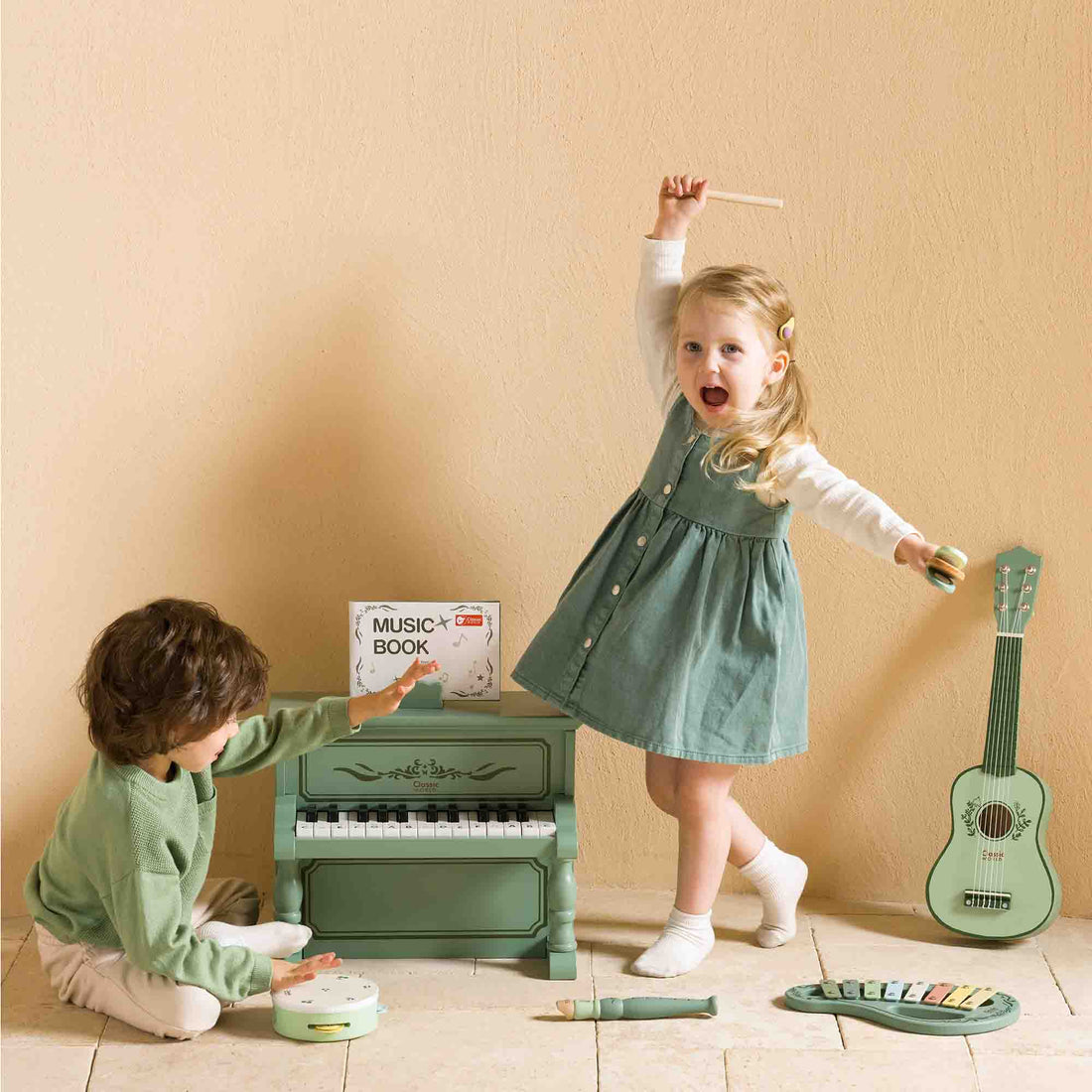 Two children playing with toy musical instruments against a beige wall.