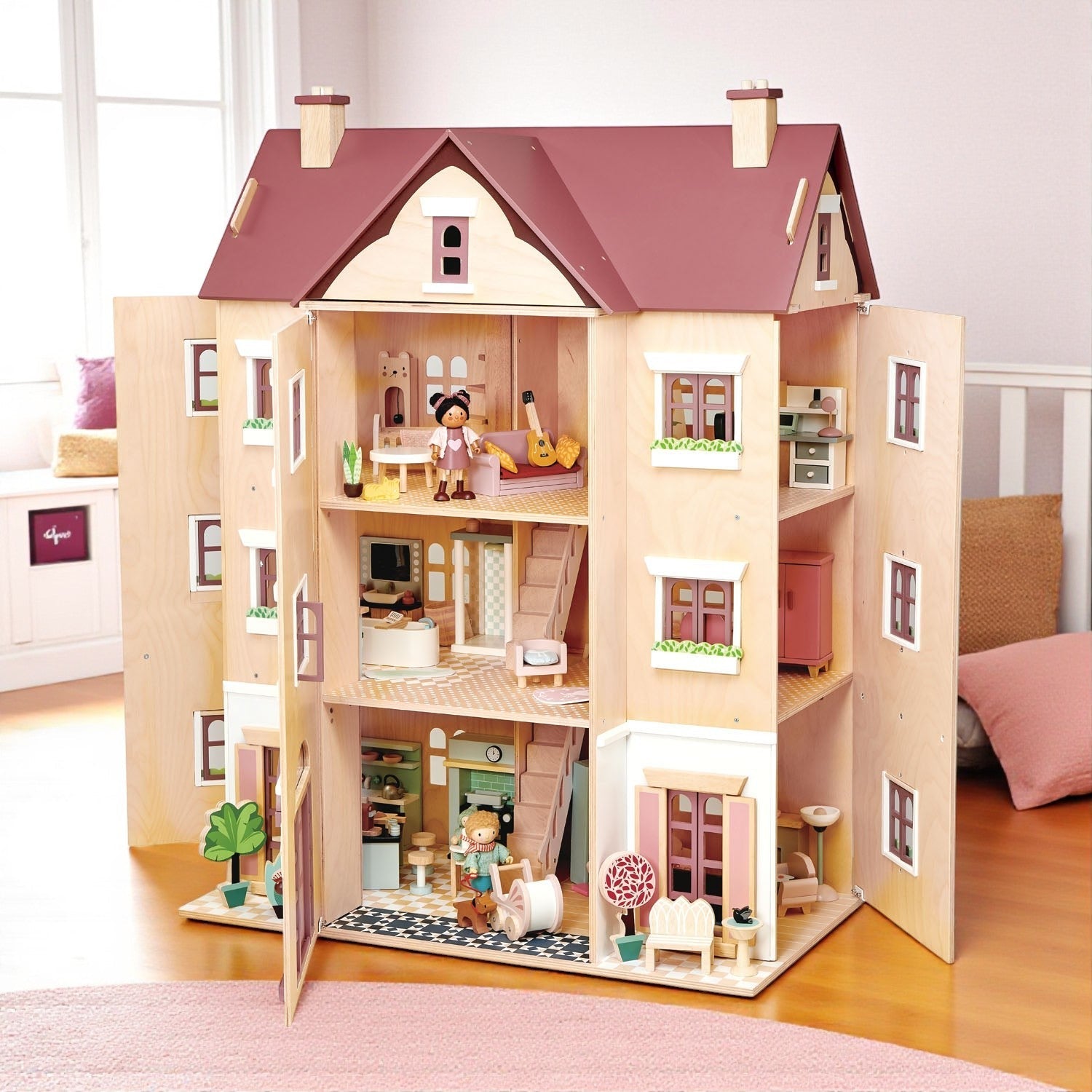 Wooden dollhouse with open doors showing interior rooms and dolls on a wooden floor.