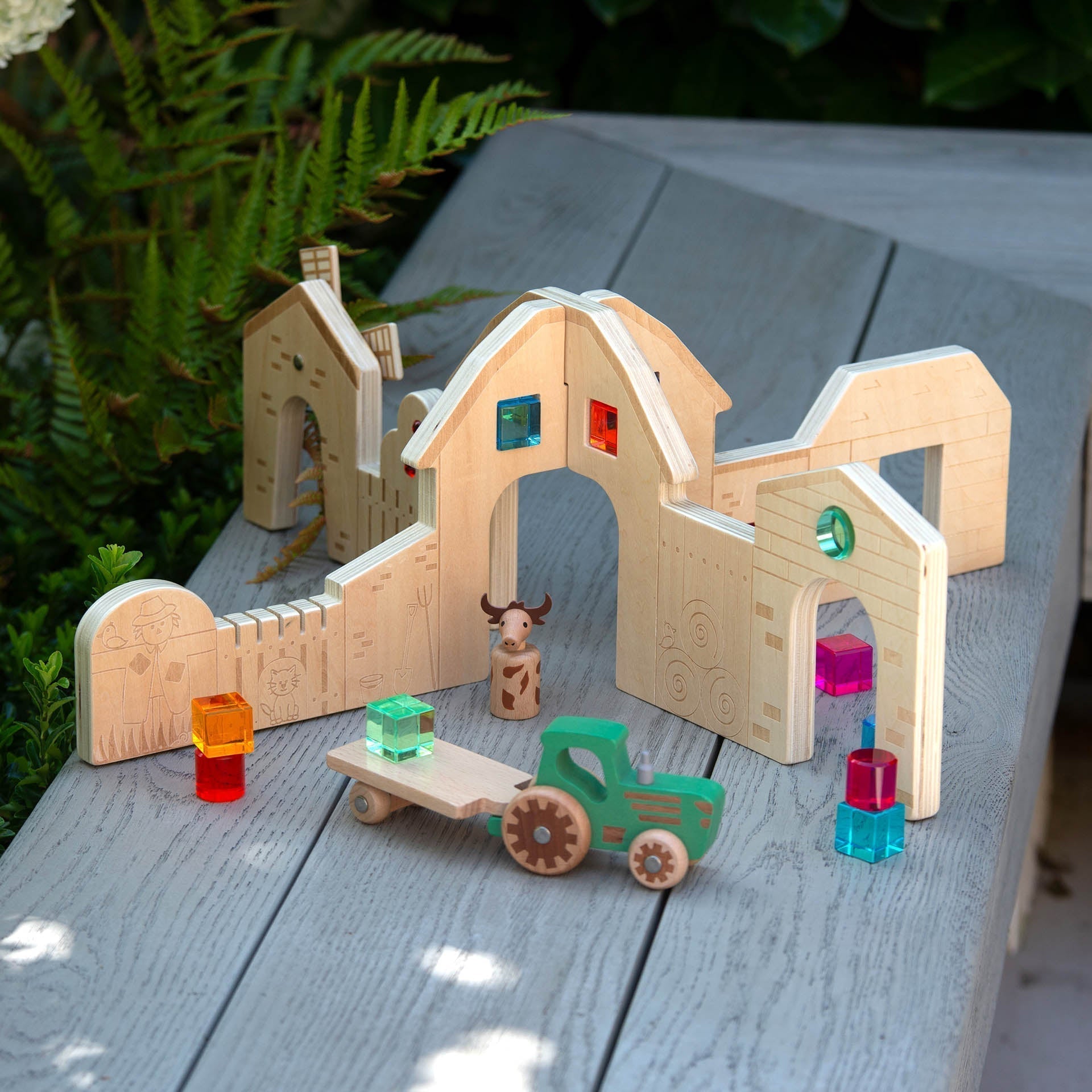 Wooden toy set with buildings and vehicles on a wooden surface
