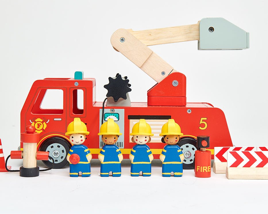 Toy fire truck with a crane and toy firefighters in front on a white background