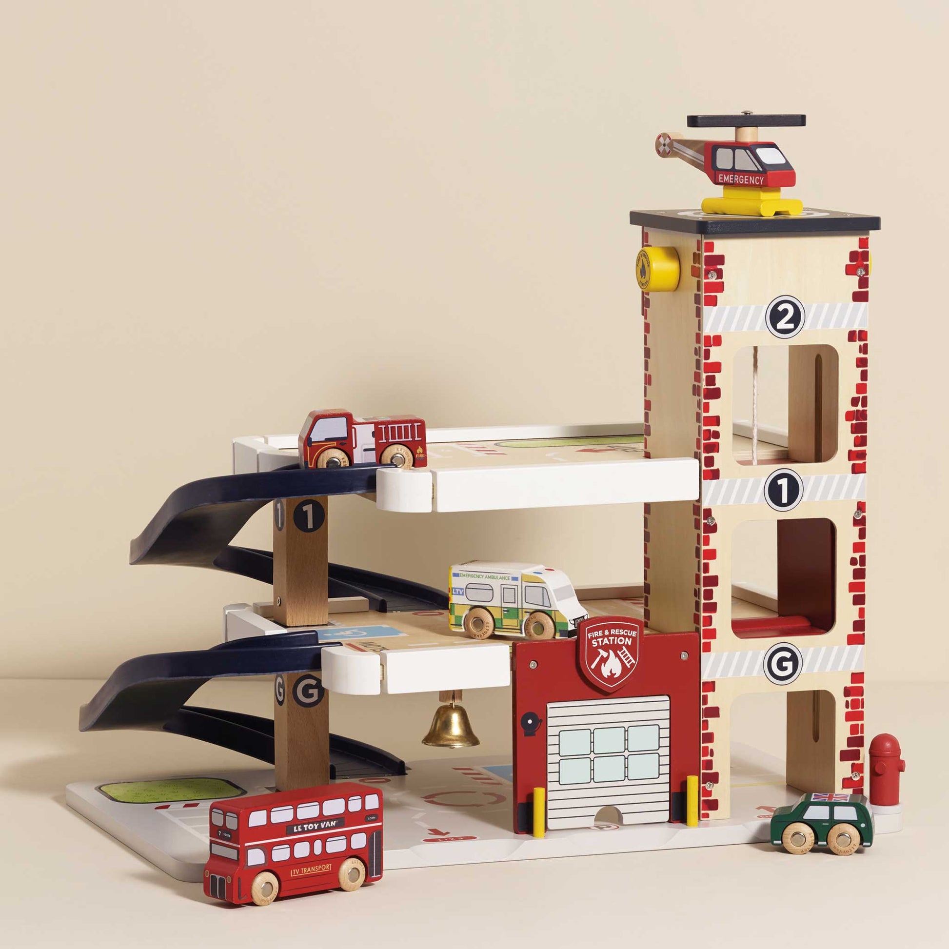 Wooden toy fire station with cars and helicopter on a beige background