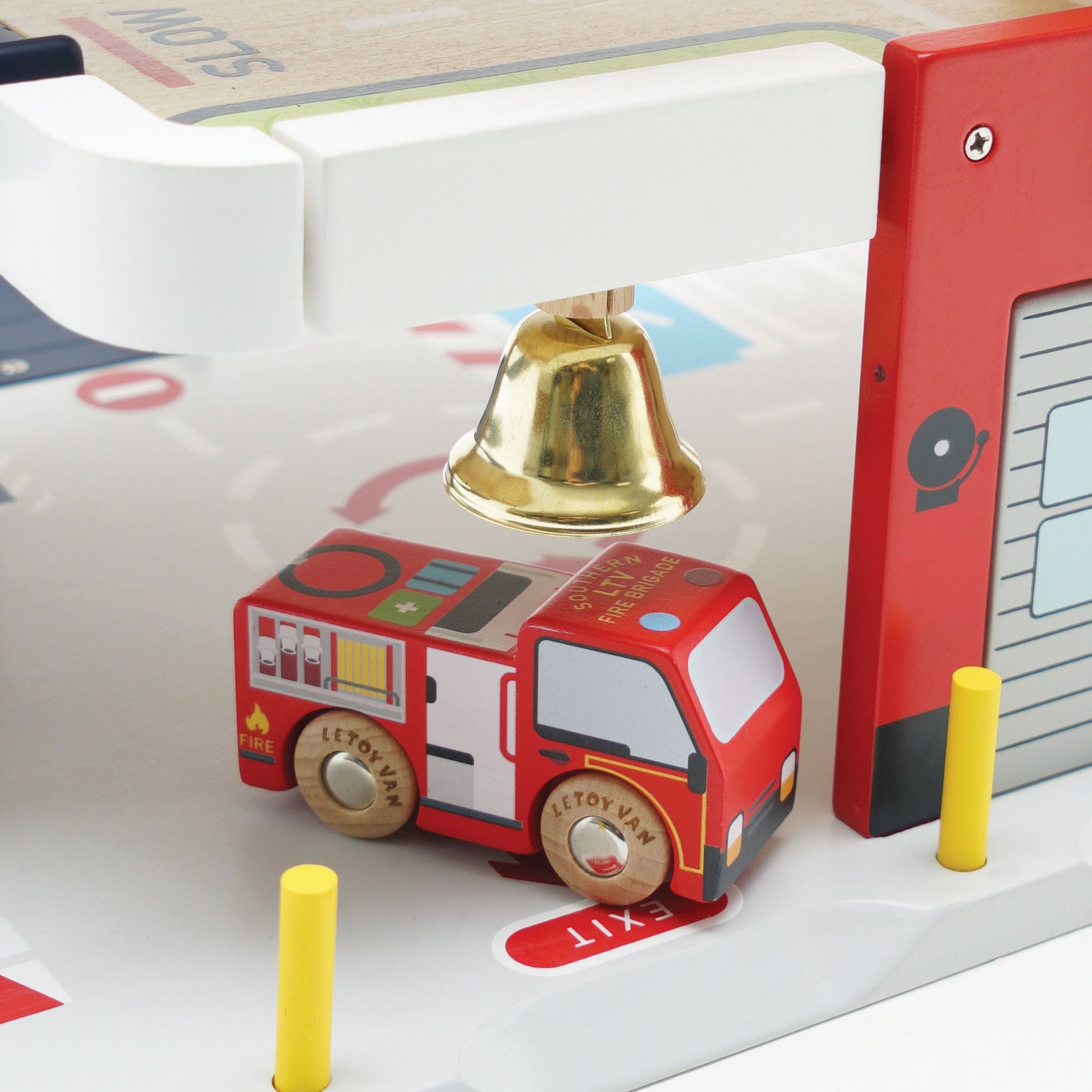 Toy fire truck with a gold bell on a white surface