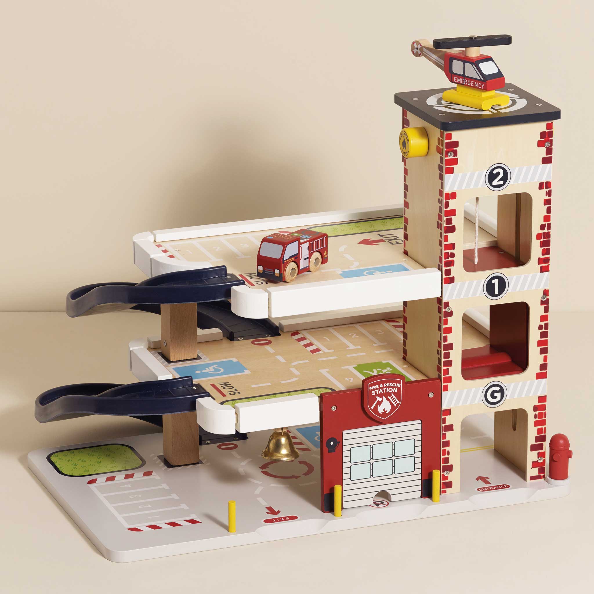 Toy fire station with cars and helicopter on a beige background