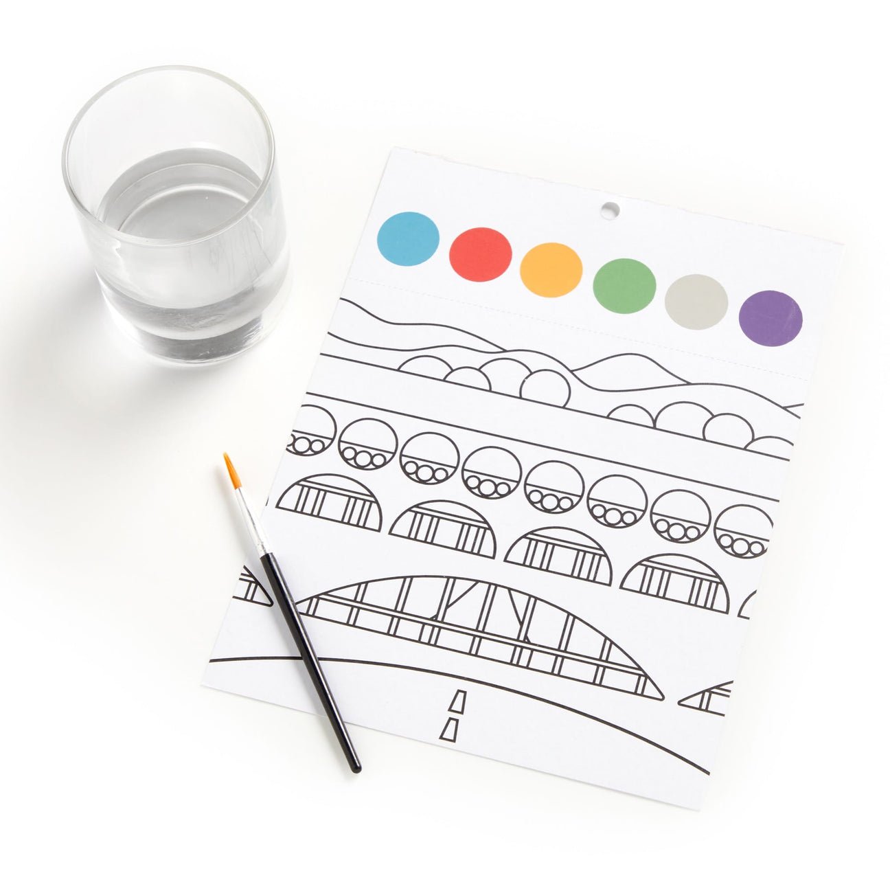 Coloring sheet with a boat design, colored circles above, and a glass of water on a white surface.