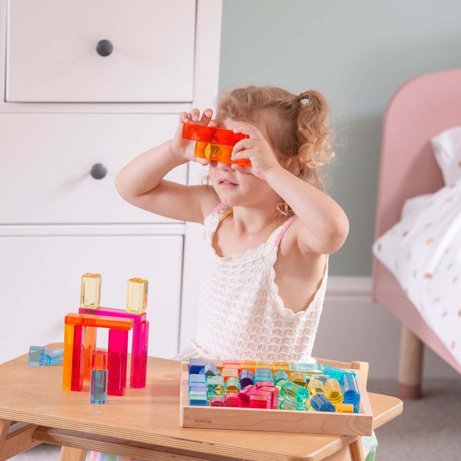 Child playing with colorful building blocks on a wooden table.
