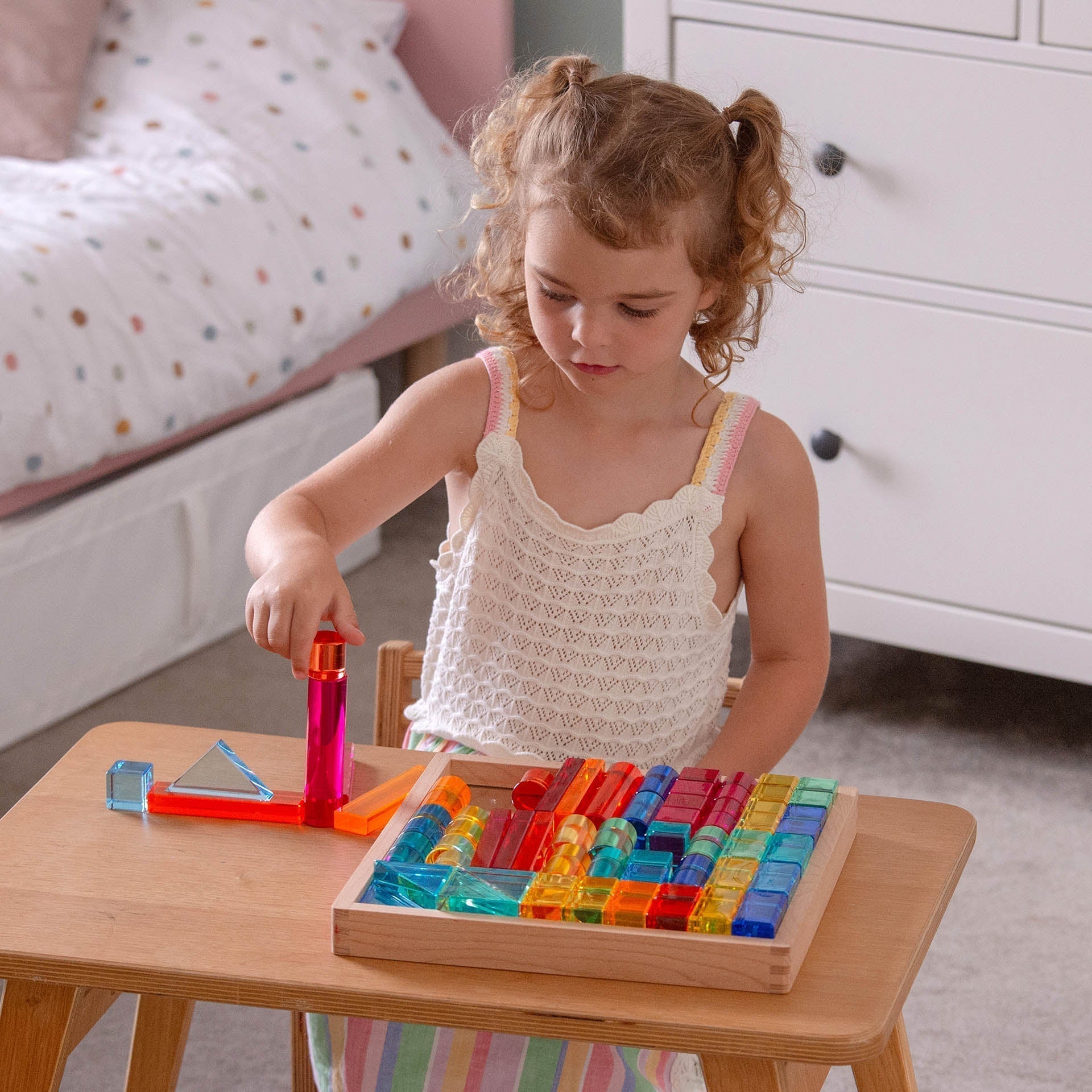 Child playing with colorful building blocks on a wooden table.