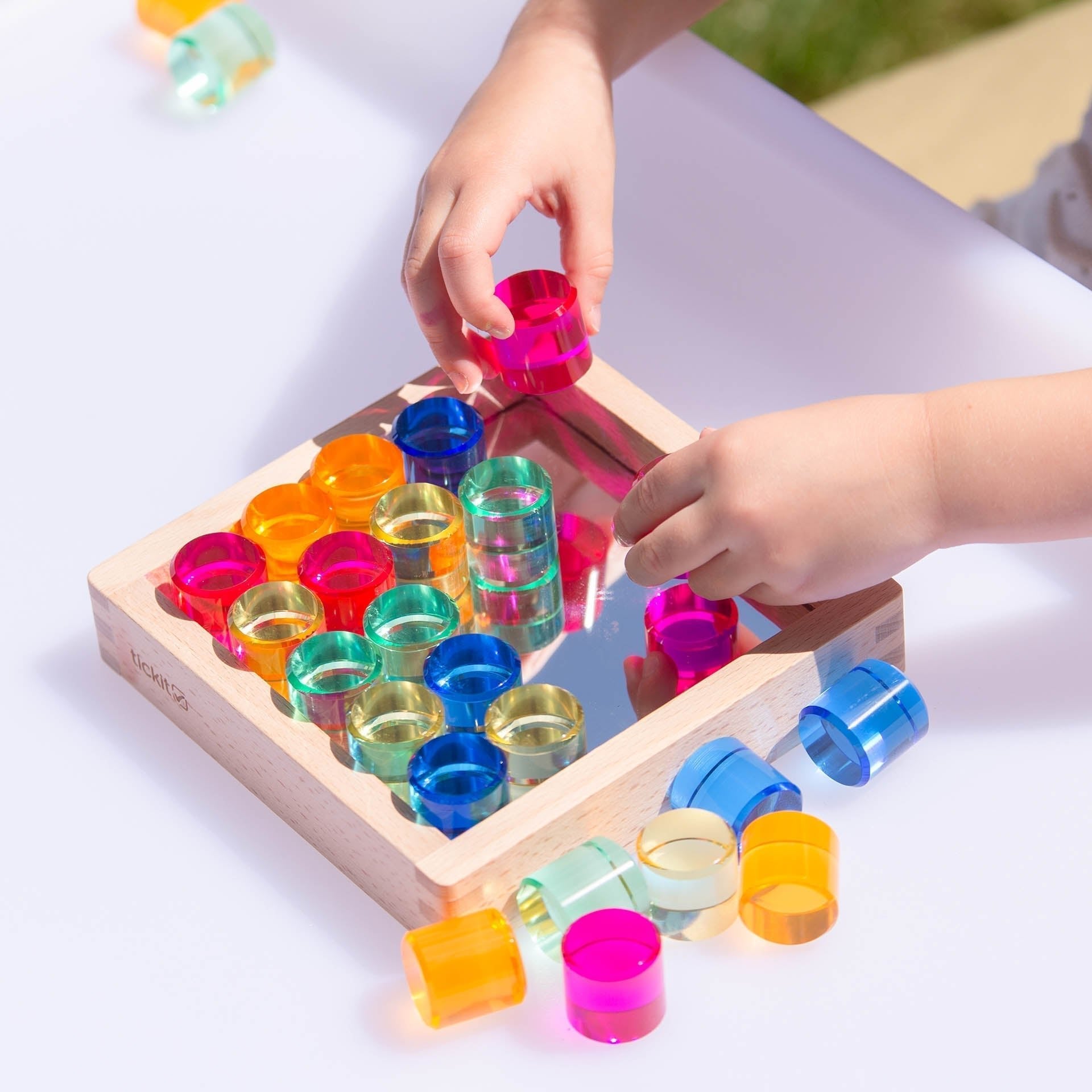 Child playing with a colorful wooden peg puzzle on a white surface.